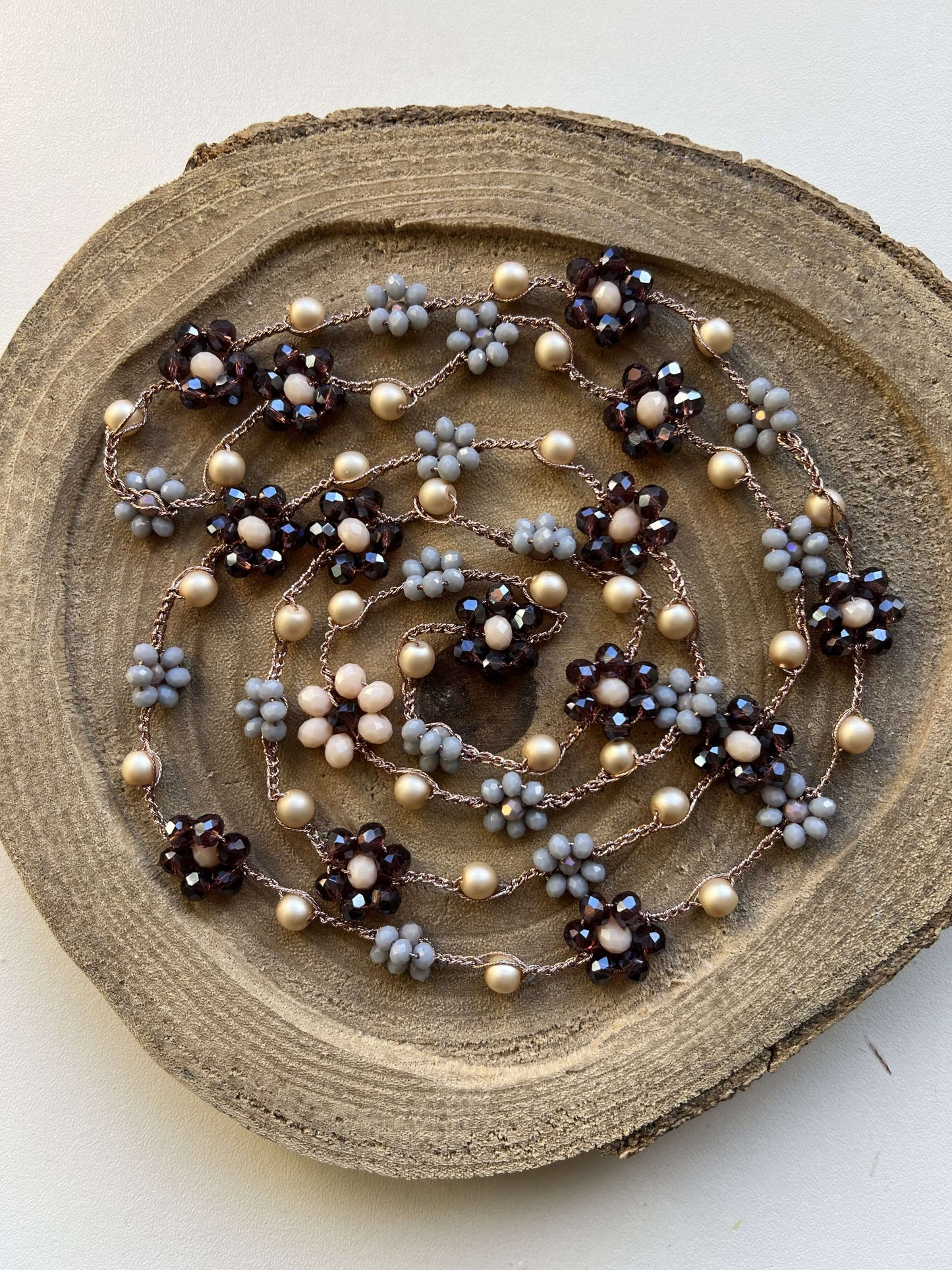 Collana artigianale in crochet con fiori viola e grigio, filato oro rosa. Viola Cenere illumina ogni look con eleganza unica.