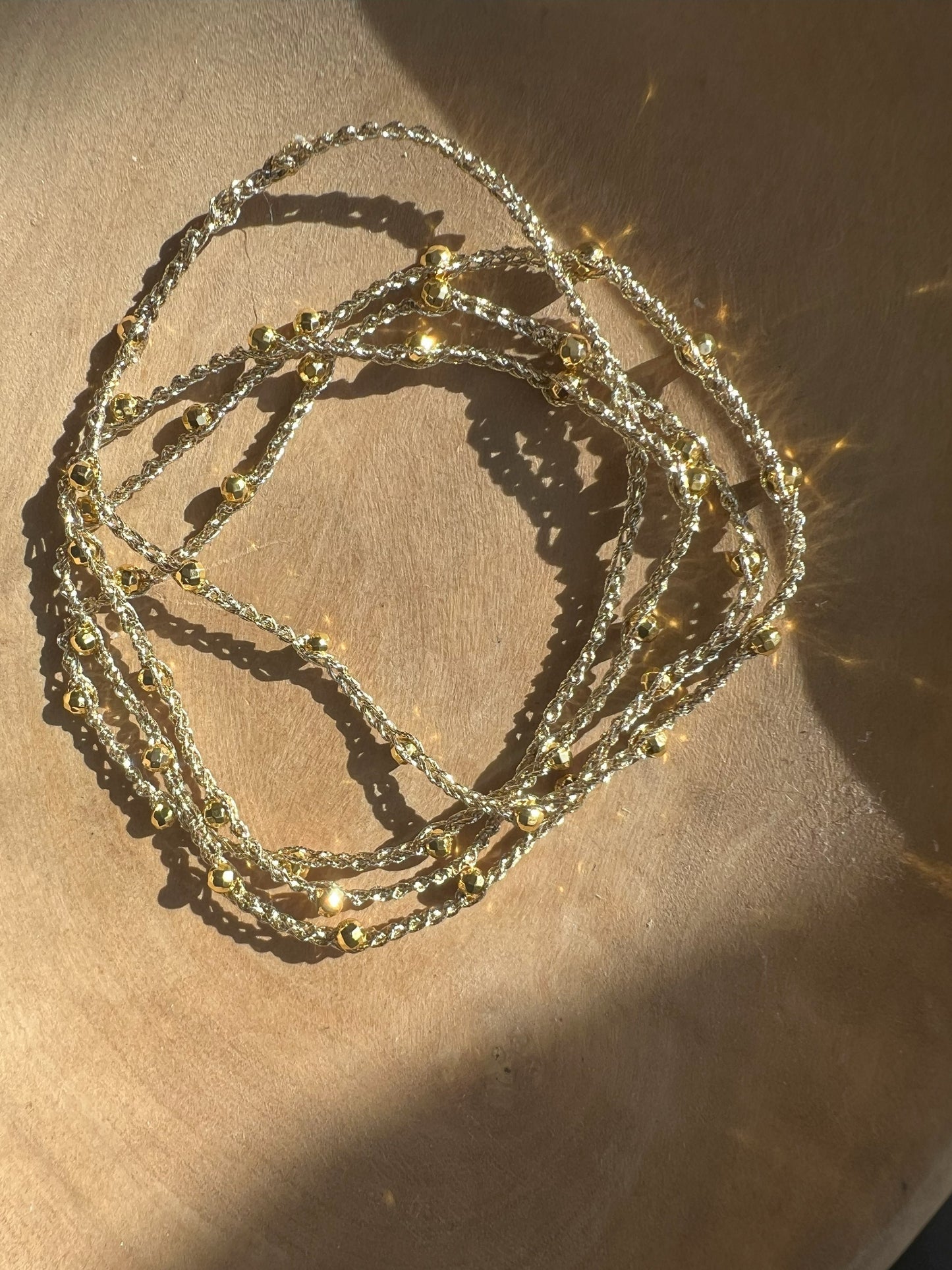 Collana minimalista in filato dorato con piccole pietre di ematite color oro, design elegante e senza chiusura, realizzata con materiali anallergici, ideale per uno stile pratico e raffinato