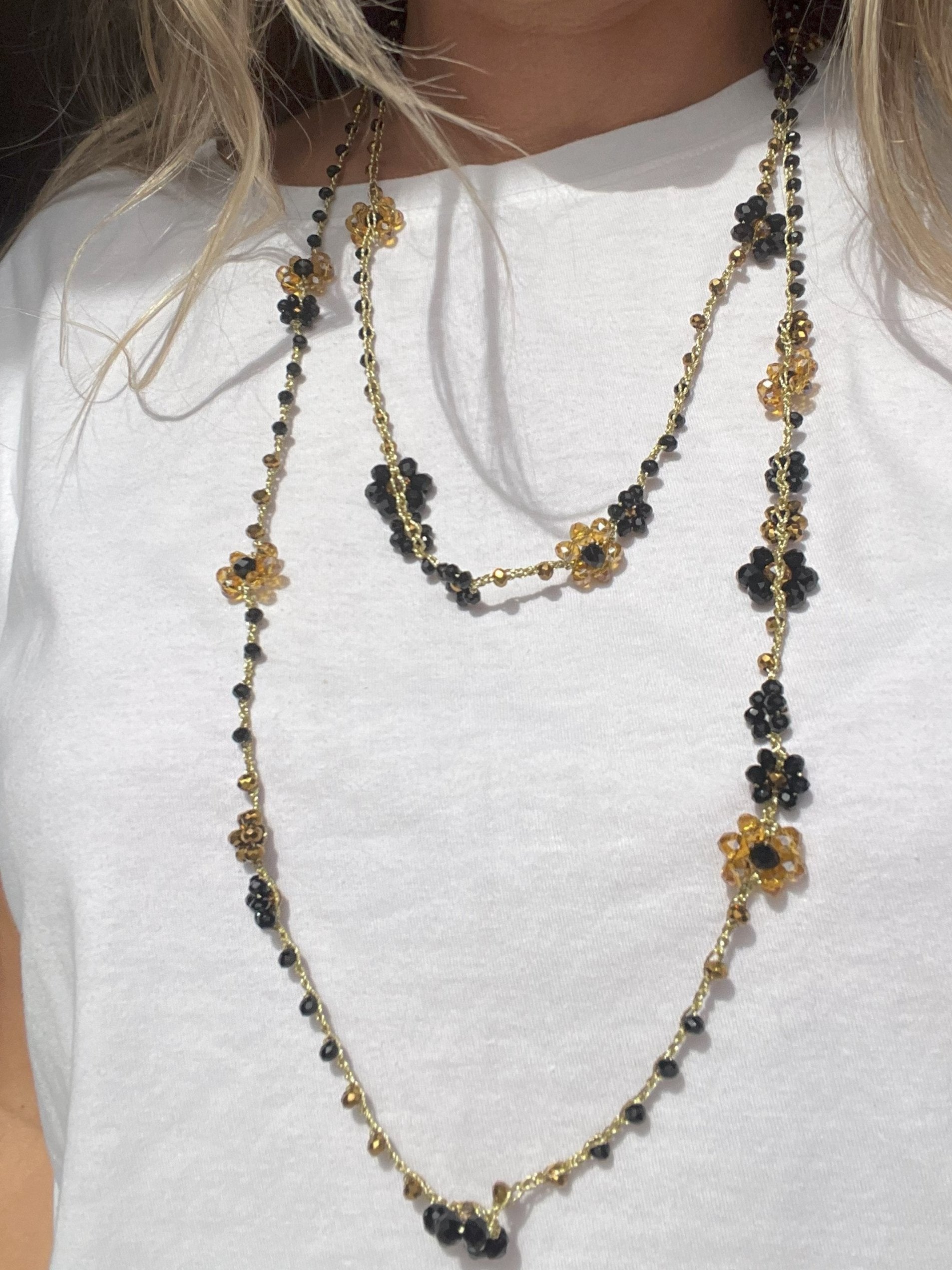 Collana lunga boho chic in oro nero con cristalli e fiori, versatile da indossare come collana o bracciale wrap, perfetta per aggiungere un tocco di eleganza e personalità al tuo look.
