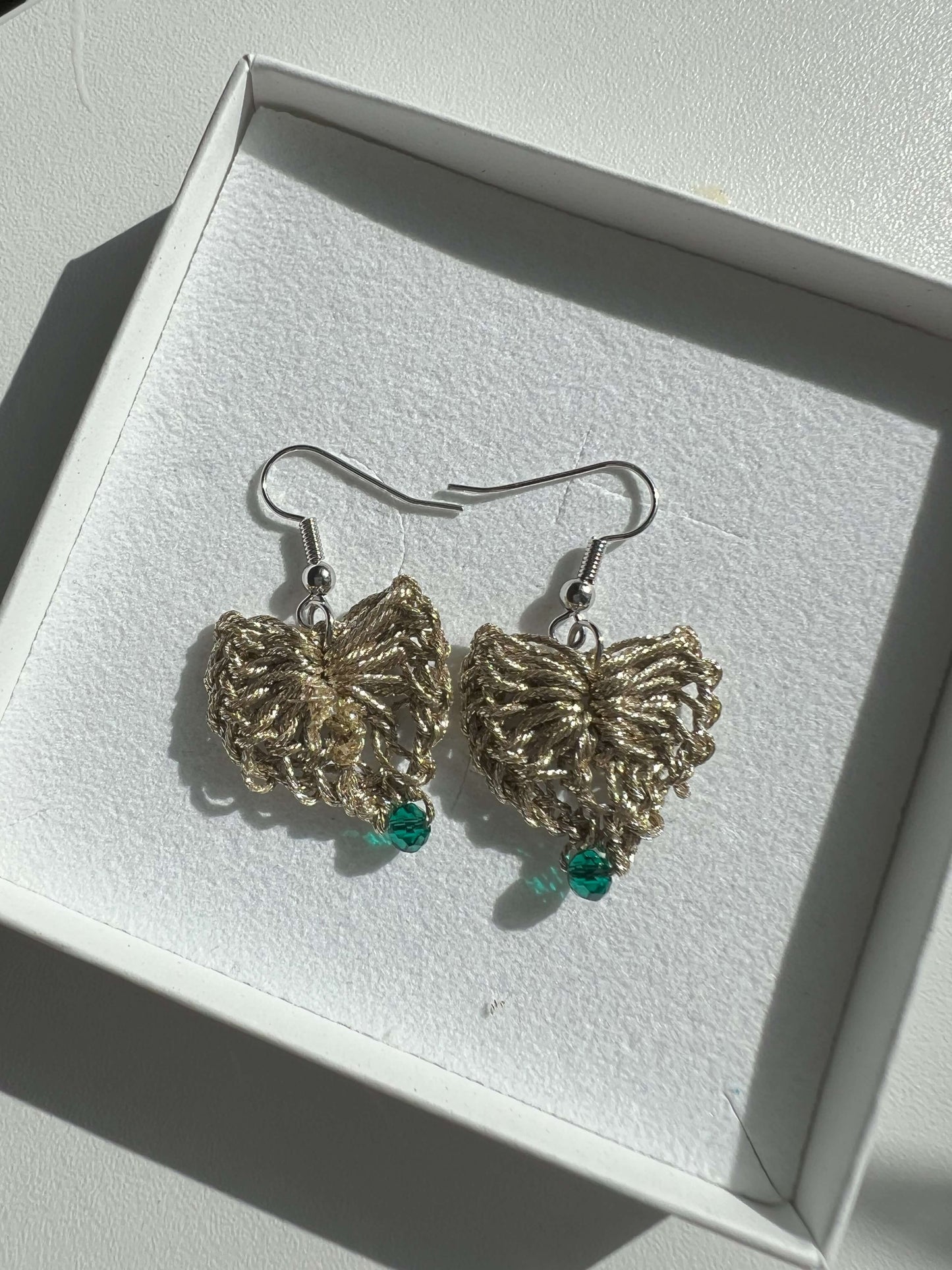 Delicati orecchini a forma di cuore in elegante color oro con un tocco di verde scuro, perfetti per aggiungere un tocco di stile e femminilità a qualsiasi outfit