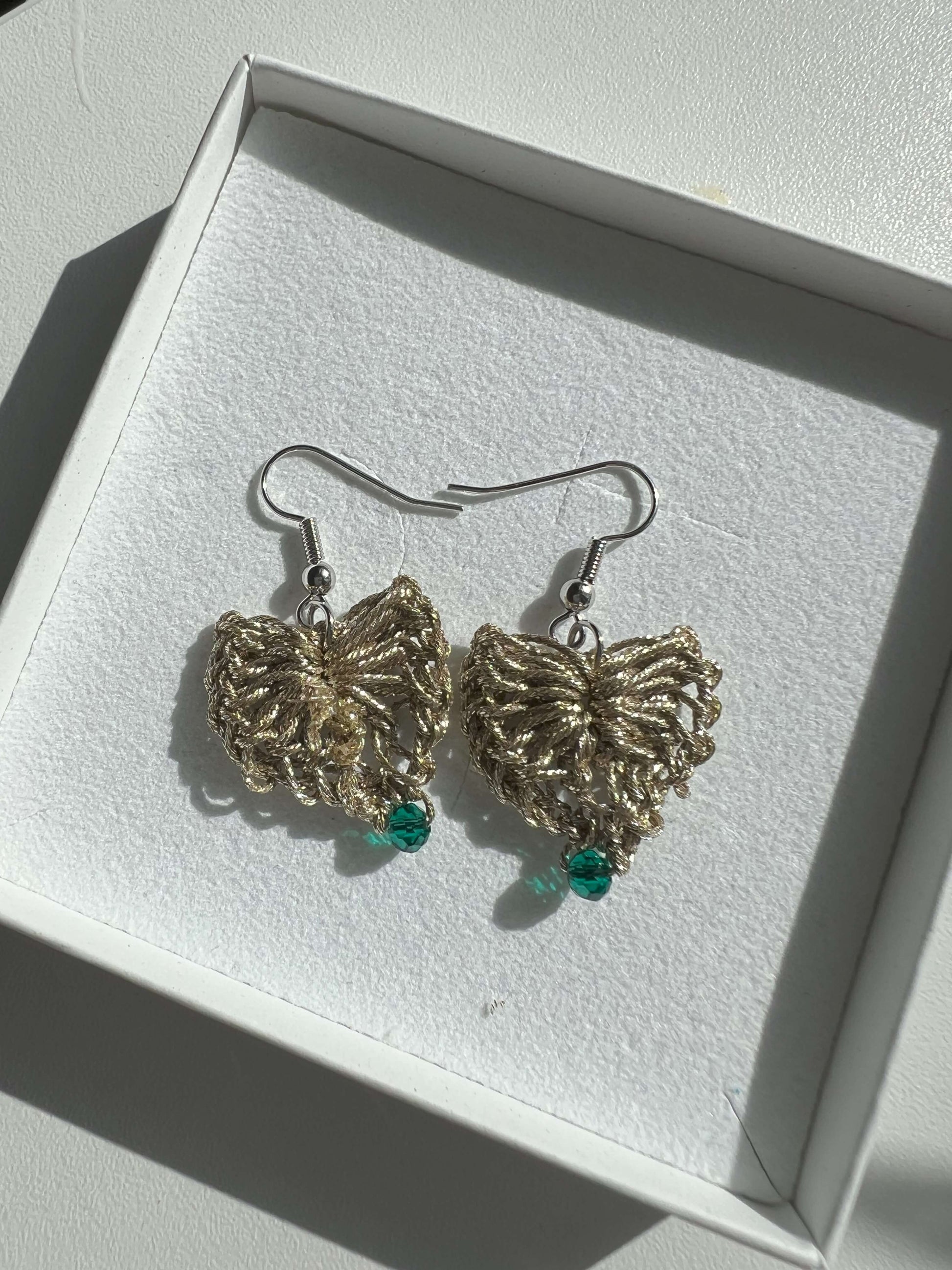 Delicati orecchini a forma di cuore in elegante color oro con un tocco di verde scuro, perfetti per aggiungere un tocco di stile e femminilità a qualsiasi outfit