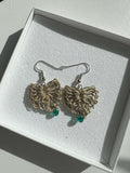 Delicati orecchini a forma di cuore in elegante color oro con un tocco di verde scuro, perfetti per aggiungere un tocco di stile e femminilità a qualsiasi outfit