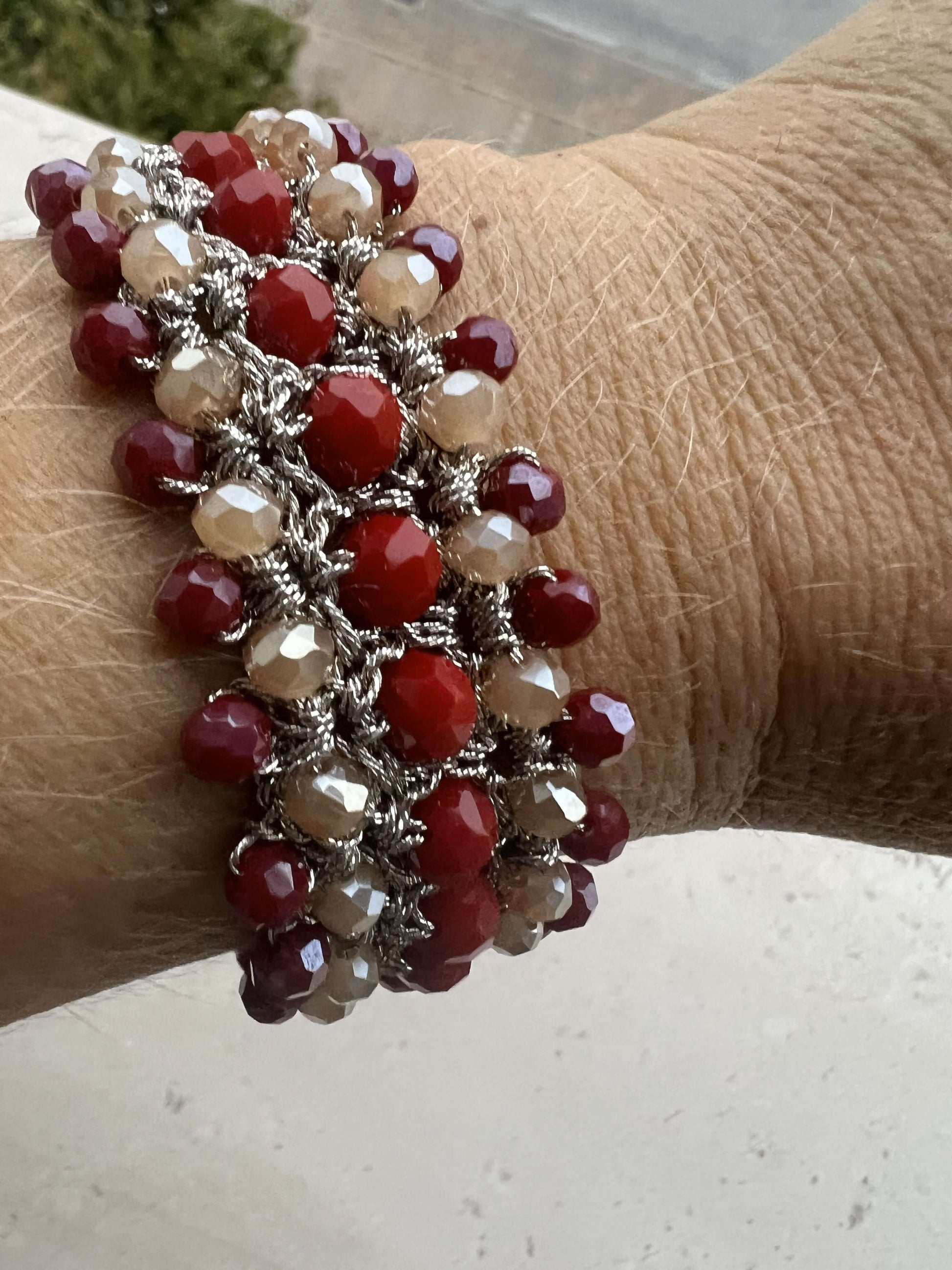 Bracciale donna con cristalli rossi e crema, lavorato a mano con filo platino. Un accessorio elegante e unico, perfetto per completare ogni look.