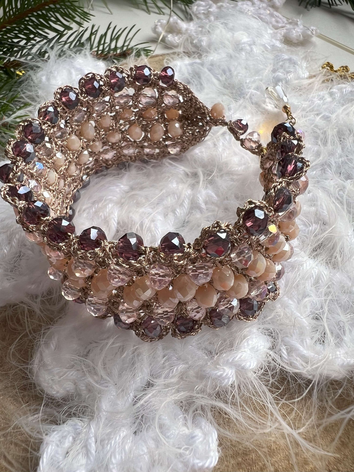 Bracciale elegante con cristalli rosa, viola e crema, filato in oro rosa e chiusura regolabile. Design raffinato, perfetto per le feste