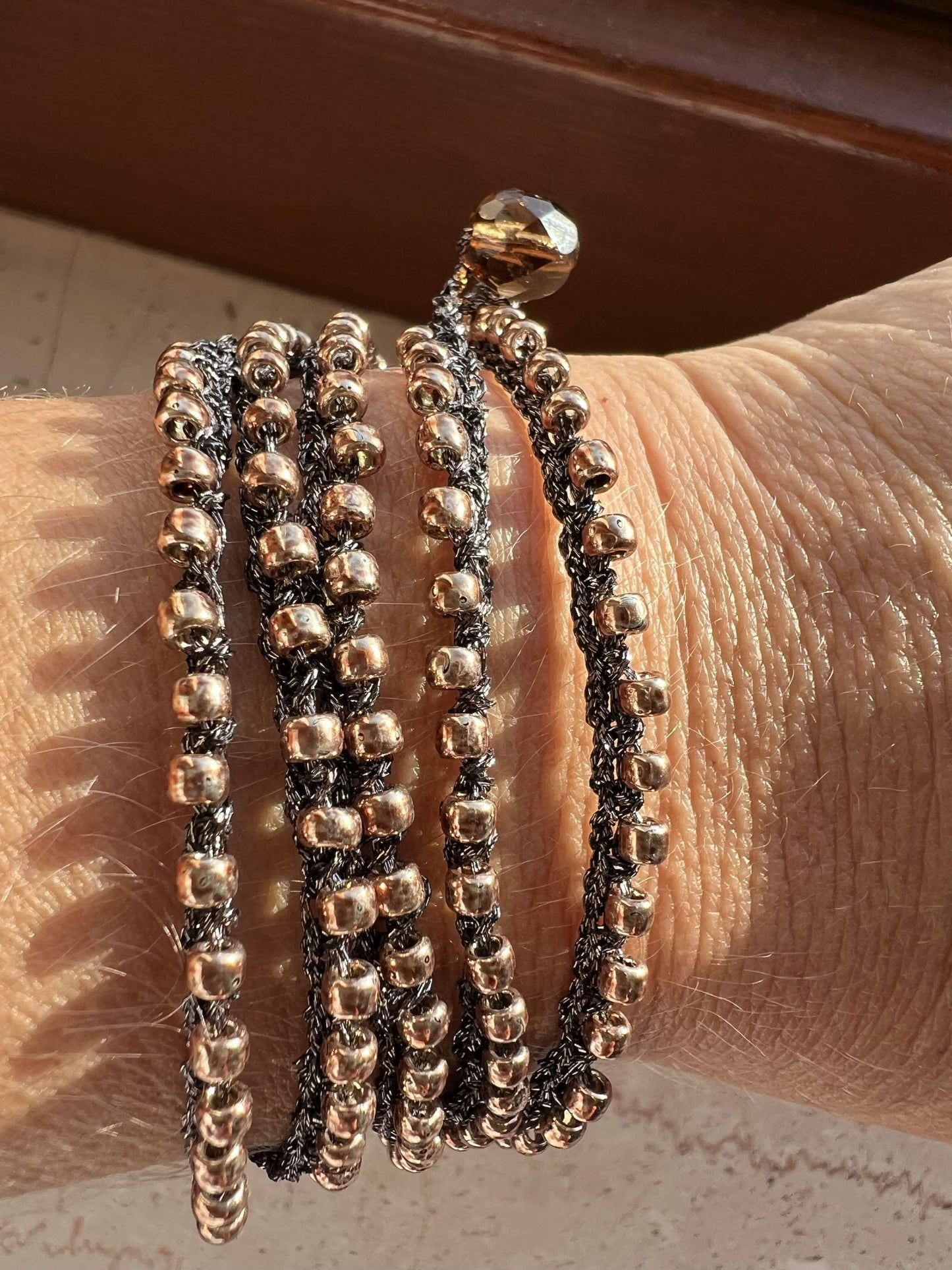 Gioiello artigianale Boho Glow, versatile come collana lunga o bracciale wrap, con perline oro Toho e chiusura in perla di vetro ceco.