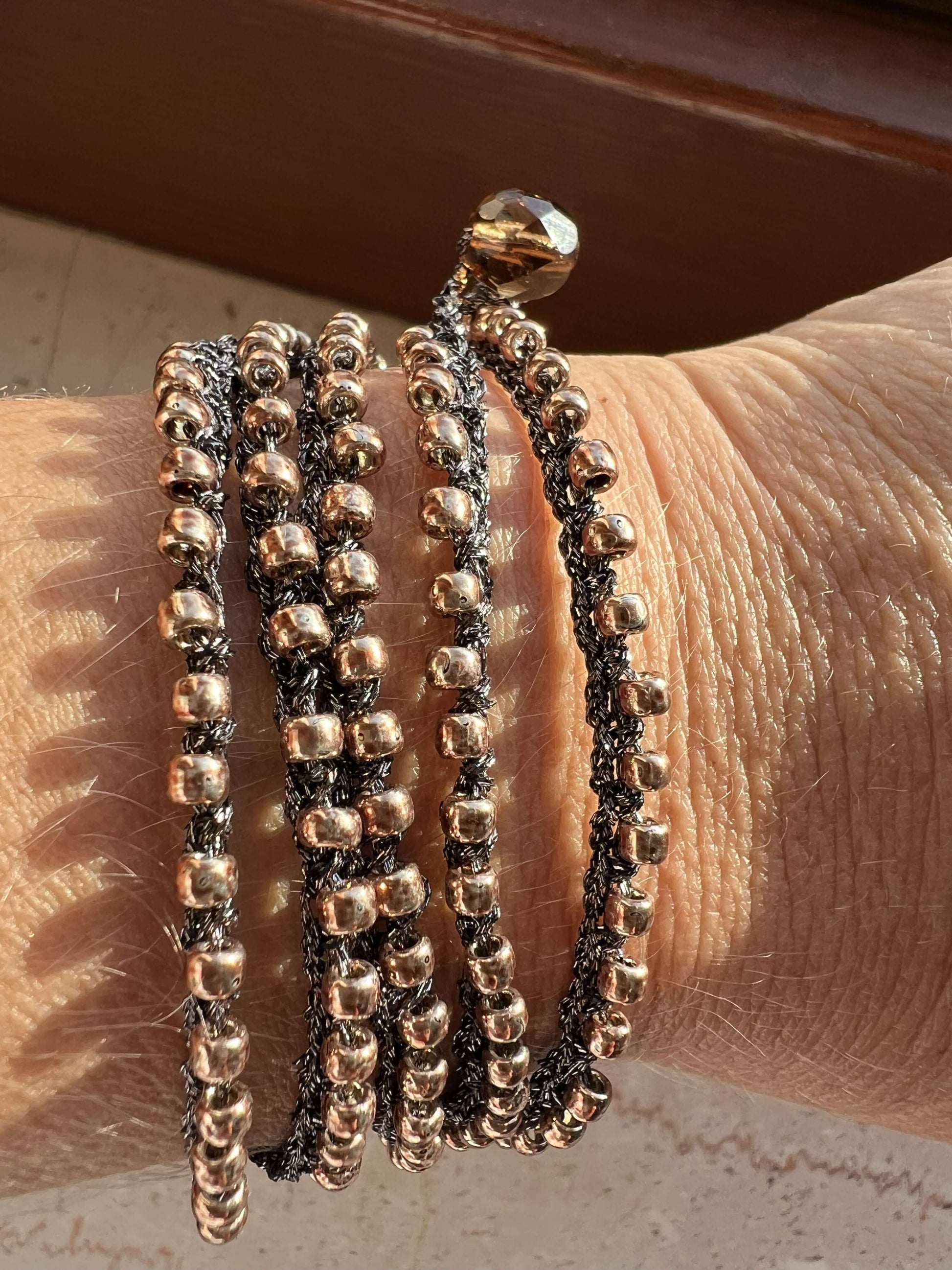 Gioiello artigianale Boho Glow, versatile come collana lunga o bracciale wrap, con perline oro Toho e chiusura in perla di vetro ceco.