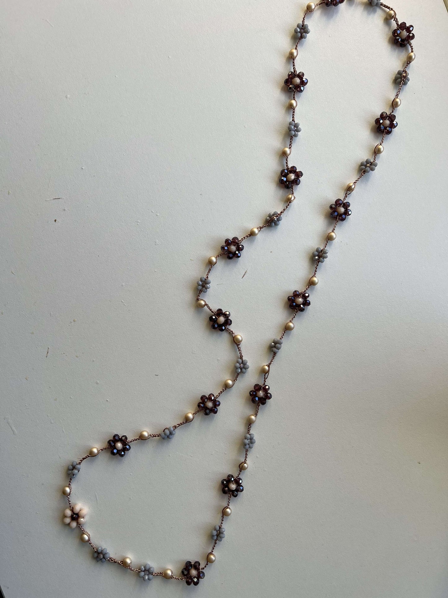 Viola Cenere, collana crochet fatta a mano con fiori viola e grigio e tocchi di oro rosa. Gioiello artigianale dal fascino delicato.