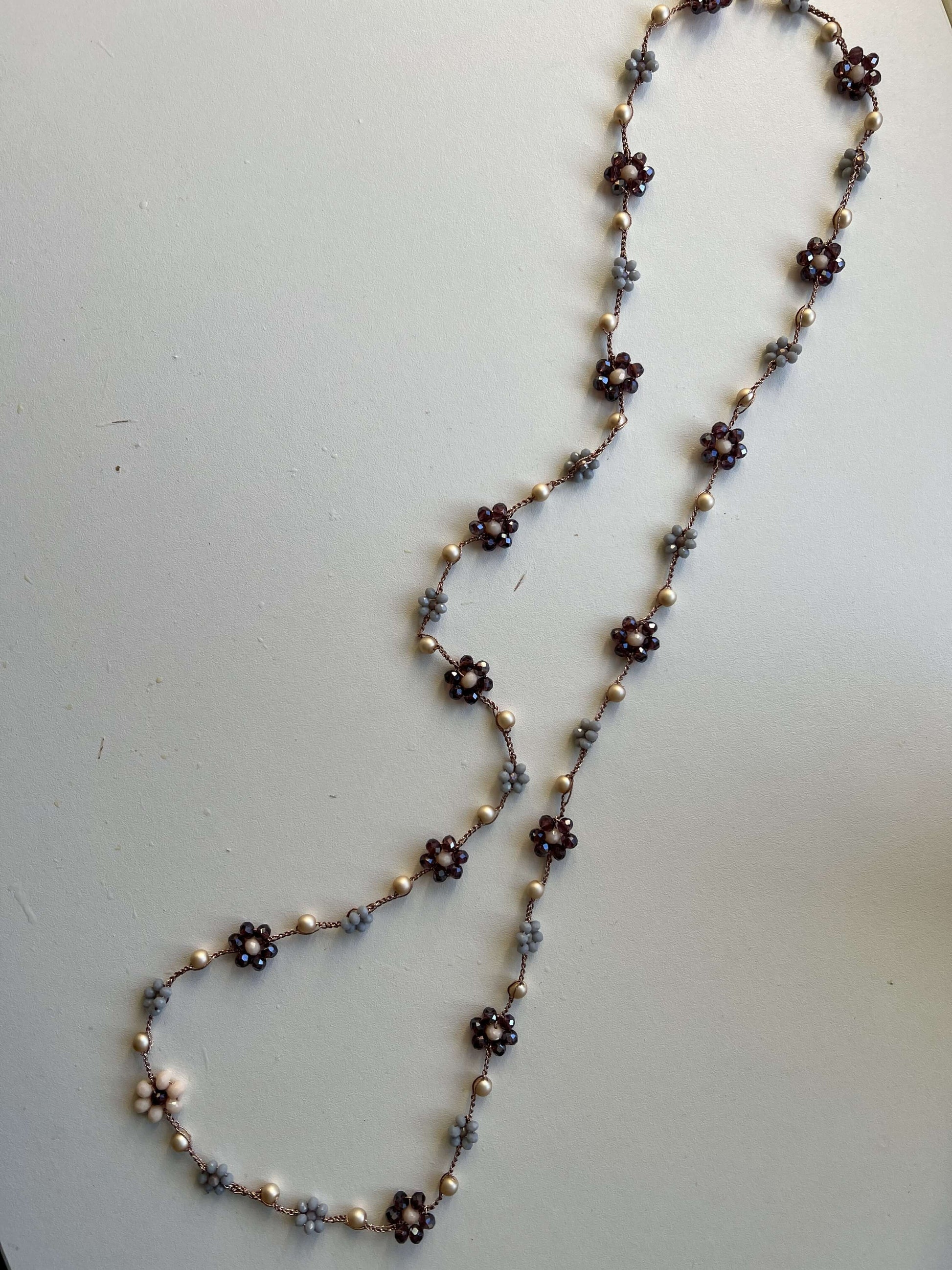 Viola Cenere, collana crochet fatta a mano con fiori viola e grigio e tocchi di oro rosa. Gioiello artigianale dal fascino delicato.