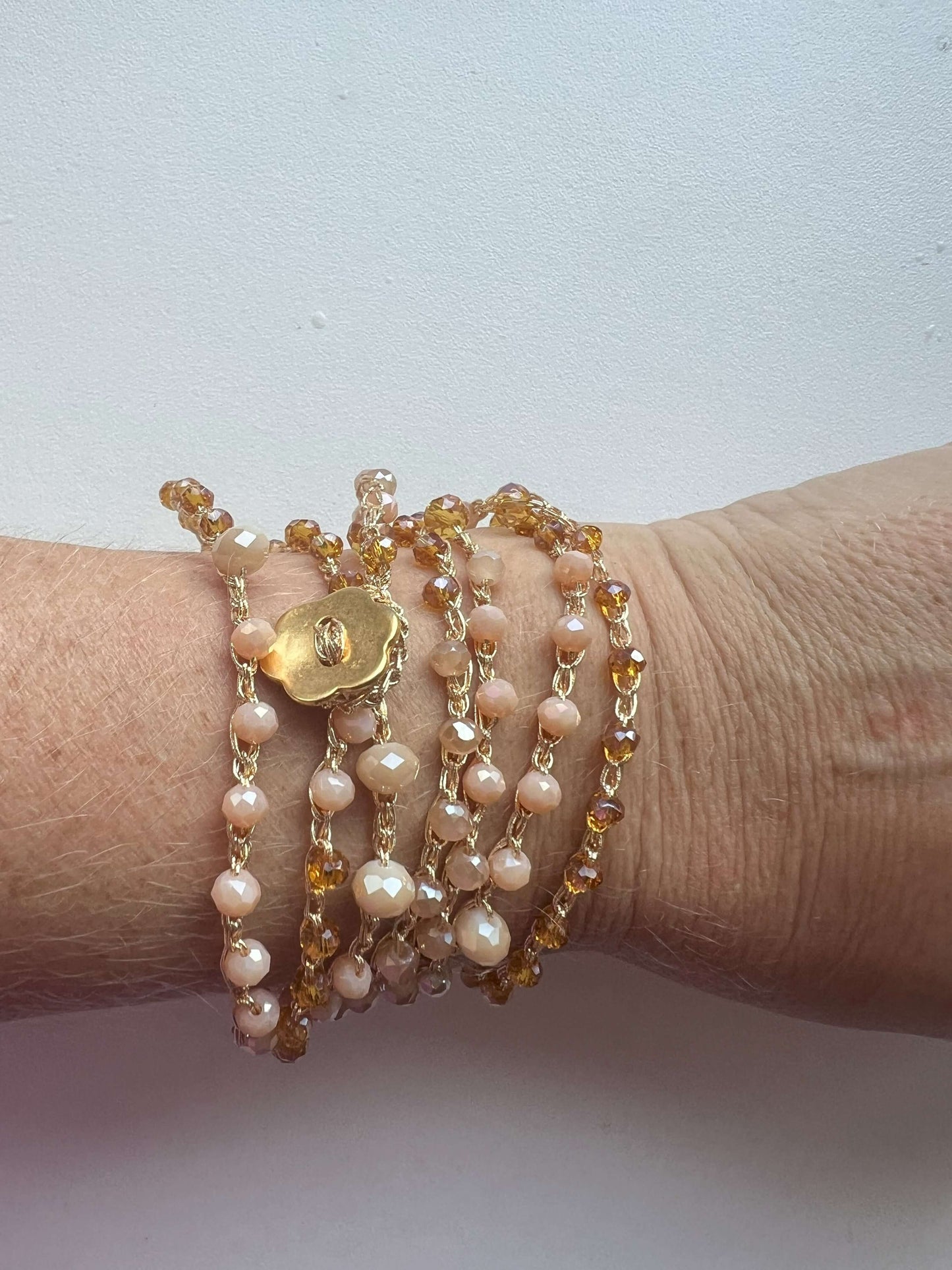 Collana boho Soleil Bloom con doppio filo di cristalli oro, bottone fiore. Elegante, versatile, da indossare come collana o bracciale multigiro.