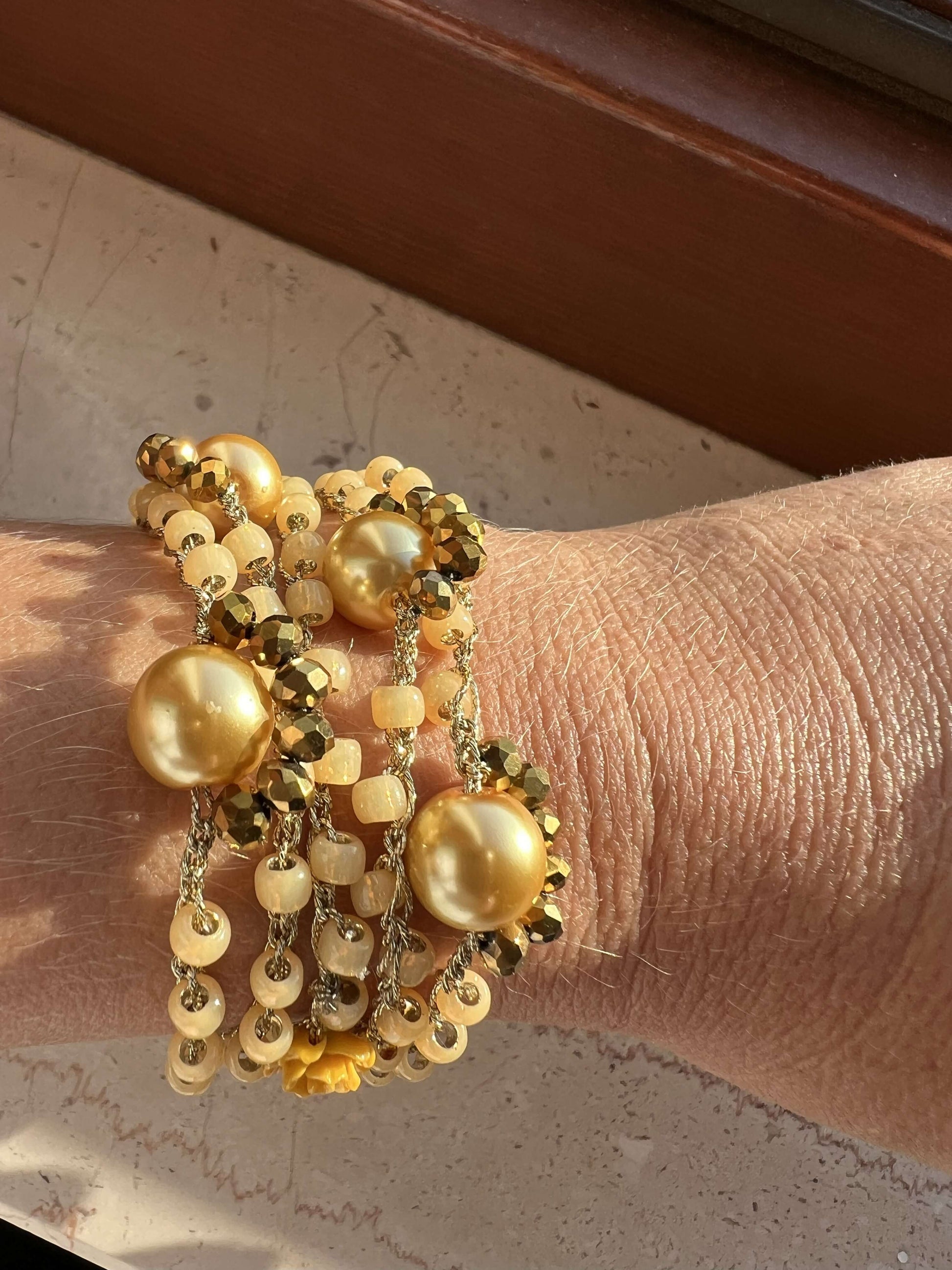 Polso con bracciale artigianale color miele e senape in perline giapponesi, collana senza chiusura indossata come wrap boho chic.