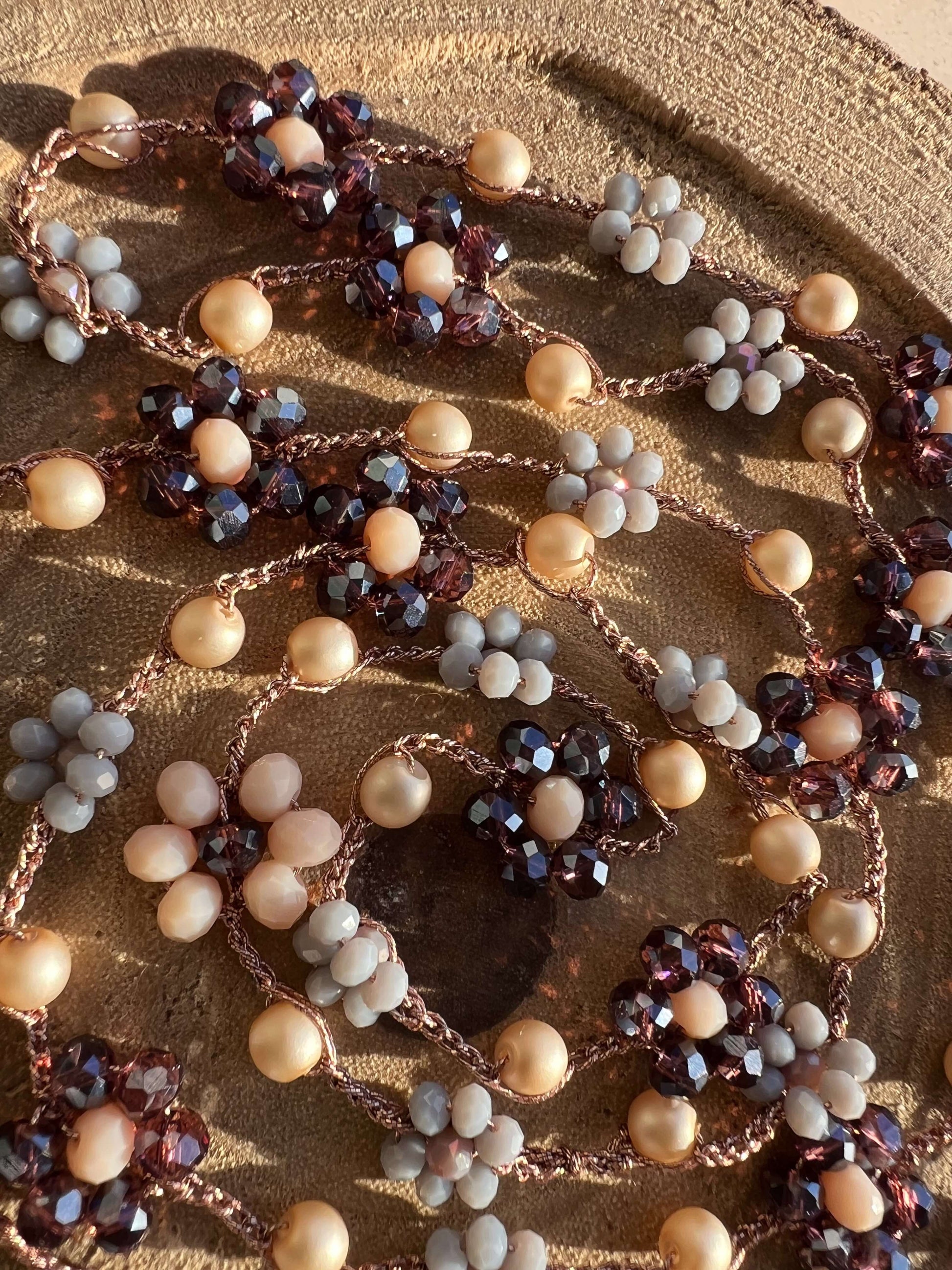 Gioiello crochet artigianale: collana Viola Cenere con fiori viola e grigio, filato oro rosa. Un’eleganza morbida e senza tempo.