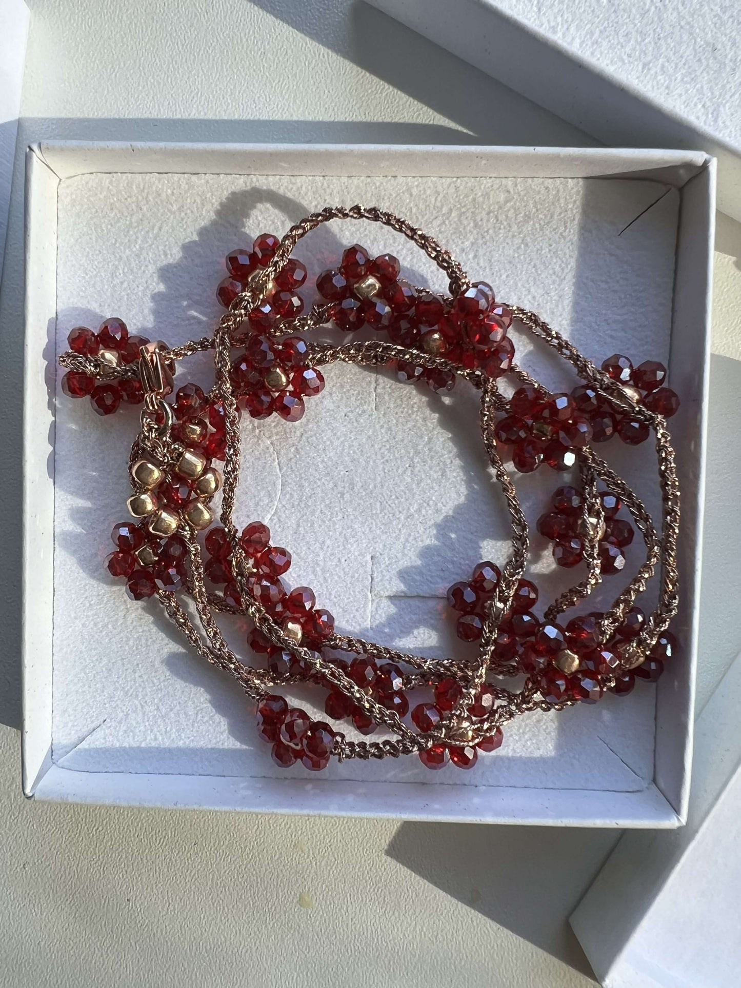 Gioiello versatile in oro rosa con fiori melograno, indossabile come collana o bracciale wrap, fatto a mano con cura.