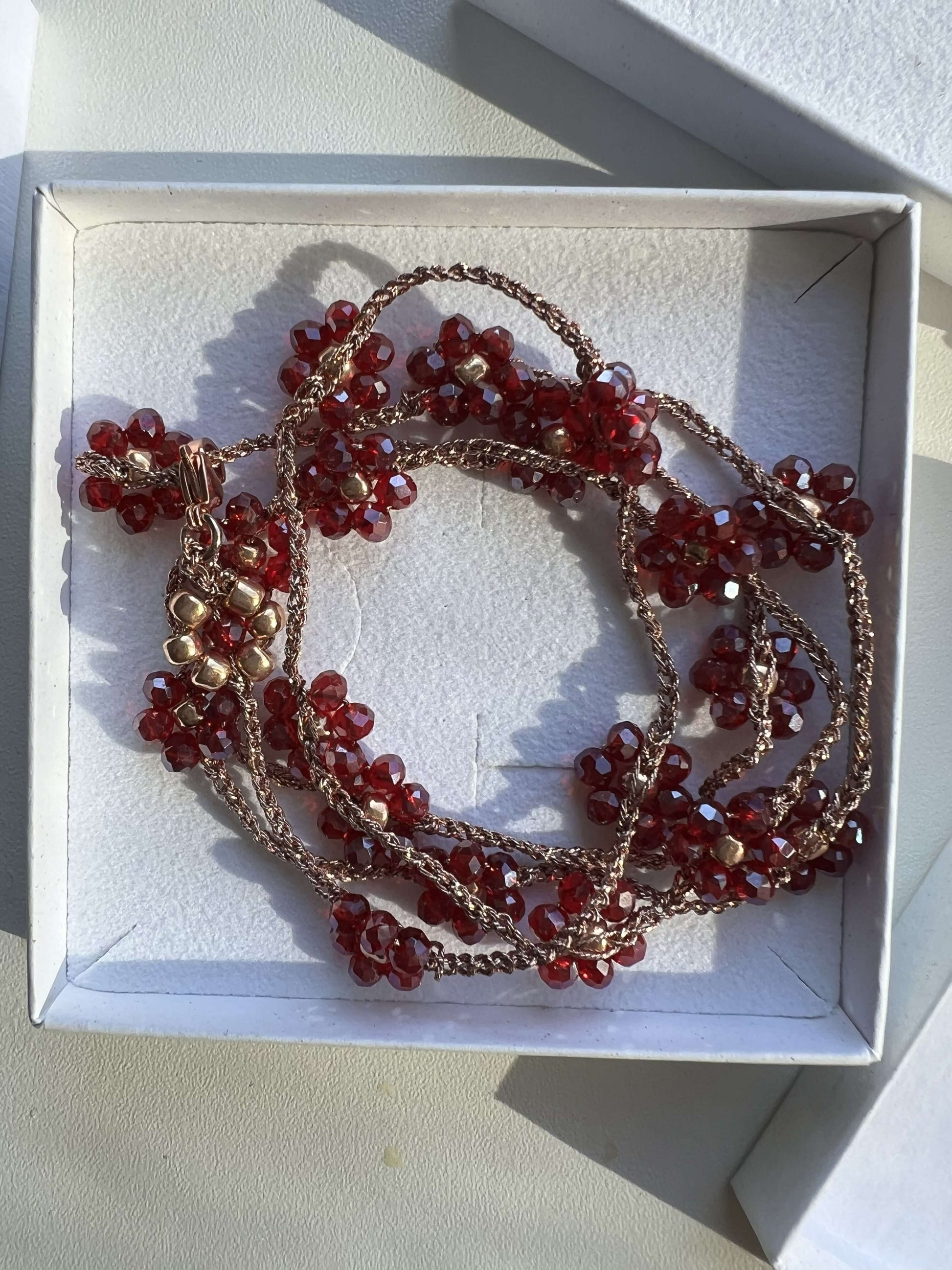 Gioiello versatile in oro rosa con fiori melograno, indossabile come collana o bracciale wrap, fatto a mano con cura.