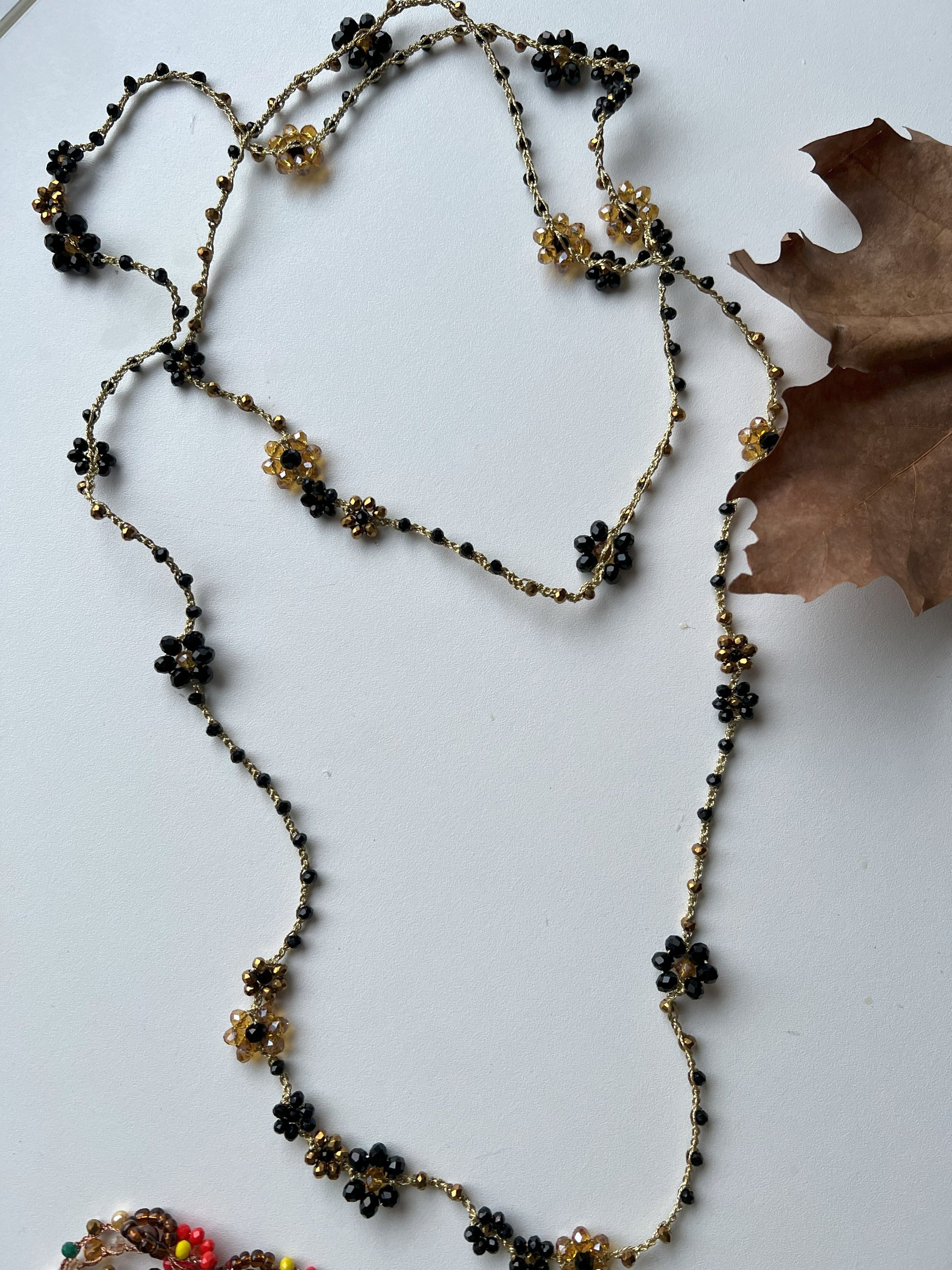 Collana lunga boho chic in oro nero con cristalli e fiori, versatile da indossare come collana o bracciale wrap, perfetta per aggiungere un tocco di eleganza e personalità al tuo look.