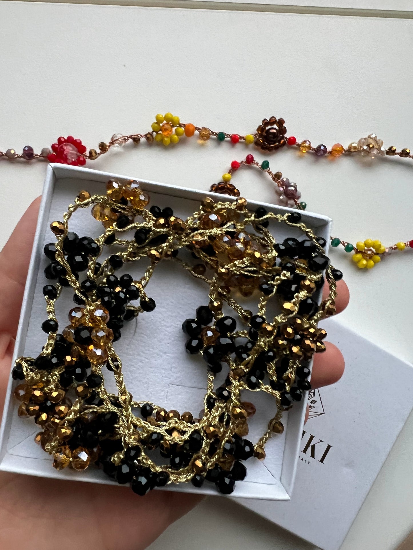 Collana lunga boho chic in oro nero con cristalli e fiori, versatile da indossare come collana o bracciale wrap, perfetta per aggiungere un tocco di eleganza e personalità al tuo look.