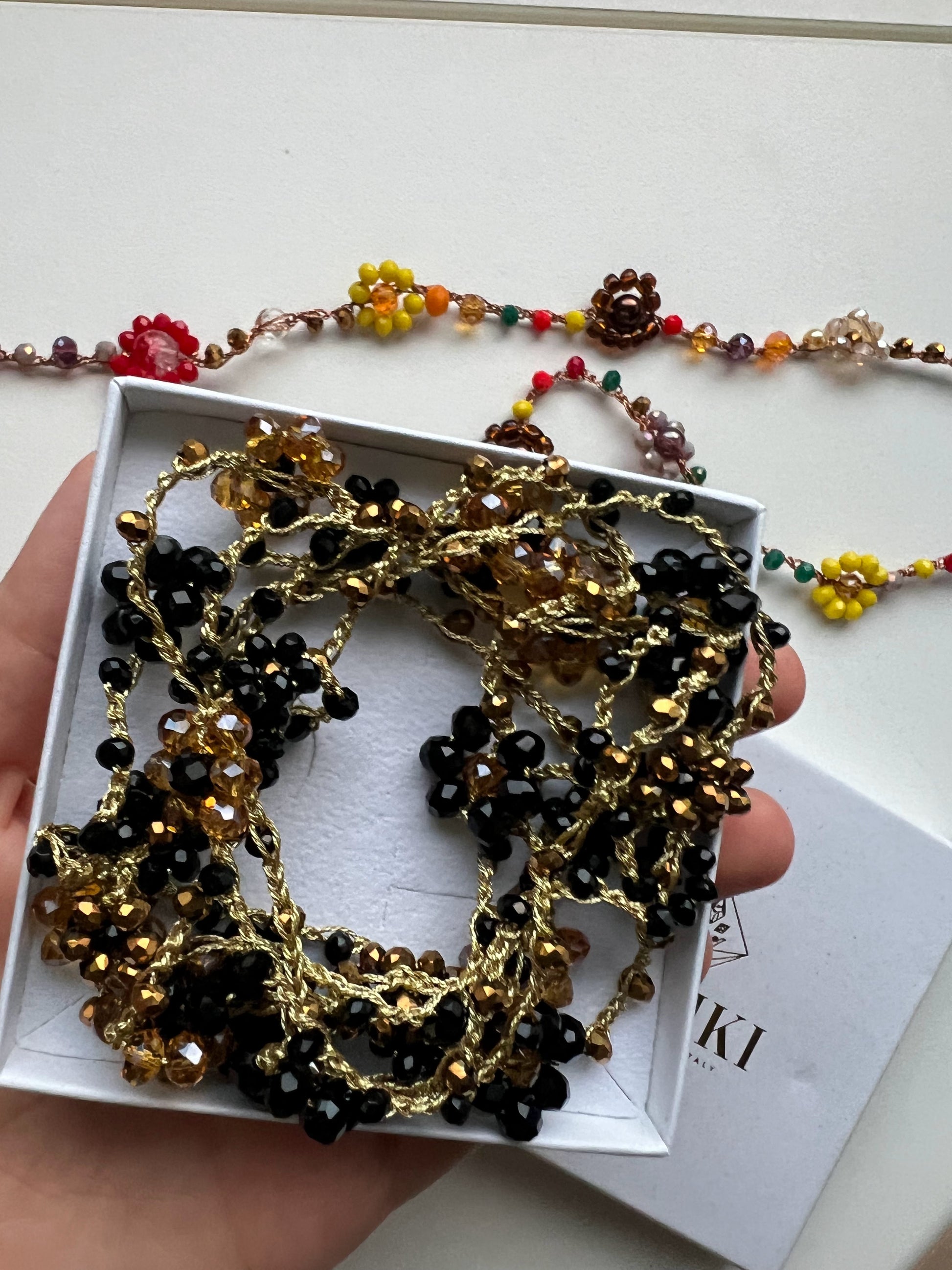 Collana lunga boho chic in oro nero con cristalli e fiori, versatile da indossare come collana o bracciale wrap, perfetta per aggiungere un tocco di eleganza e personalità al tuo look.