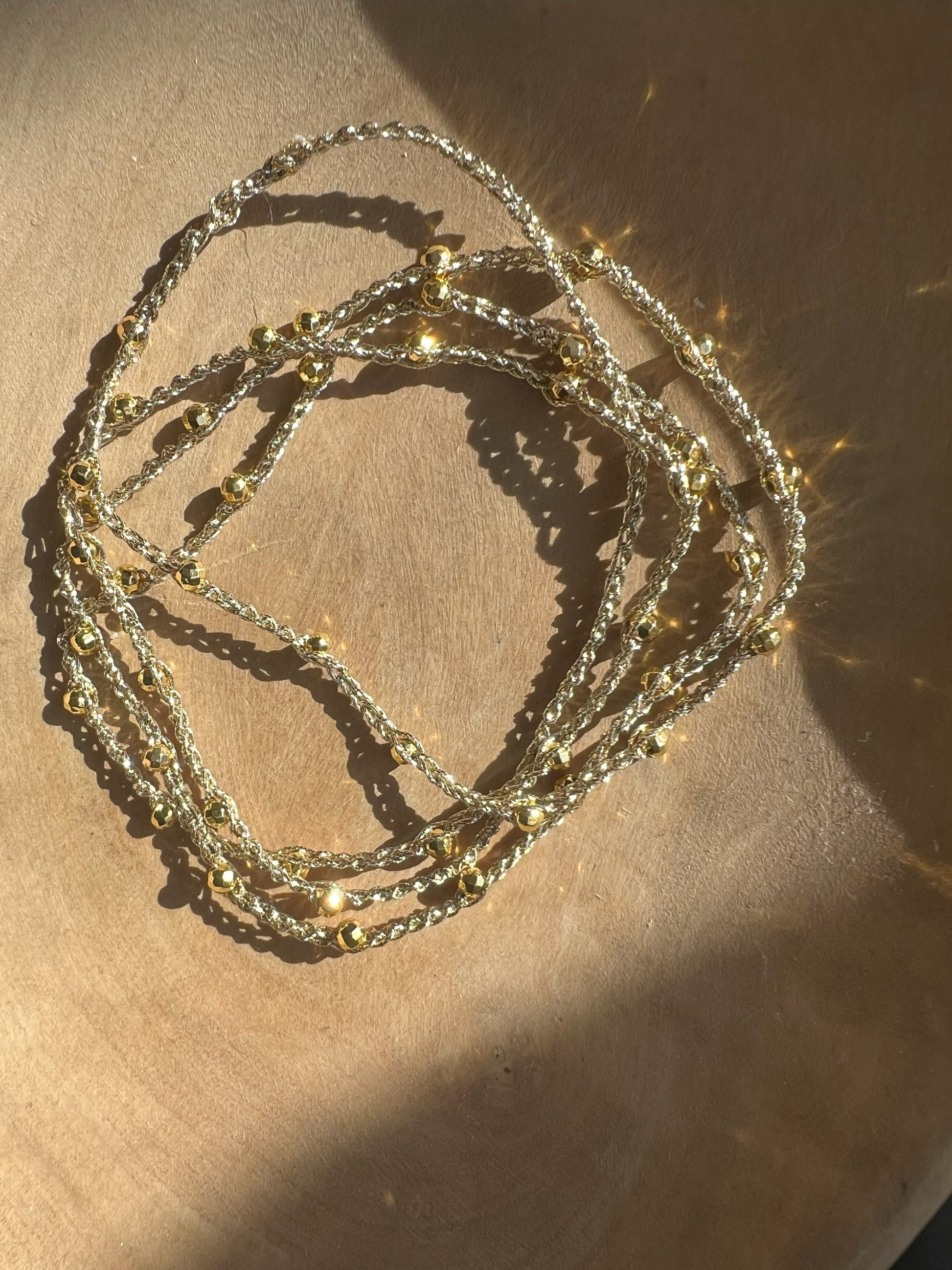 Collana minimalista in filato dorato con piccole pietre di ematite color oro, design elegante e senza chiusura, realizzata con materiali anallergici, ideale per uno stile pratico e raffinato