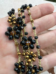 Collana lunga boho chic in oro nero con cristalli e fiori, versatile da indossare come collana o bracciale wrap, perfetta per aggiungere un tocco di eleganza e personalità al tuo look.