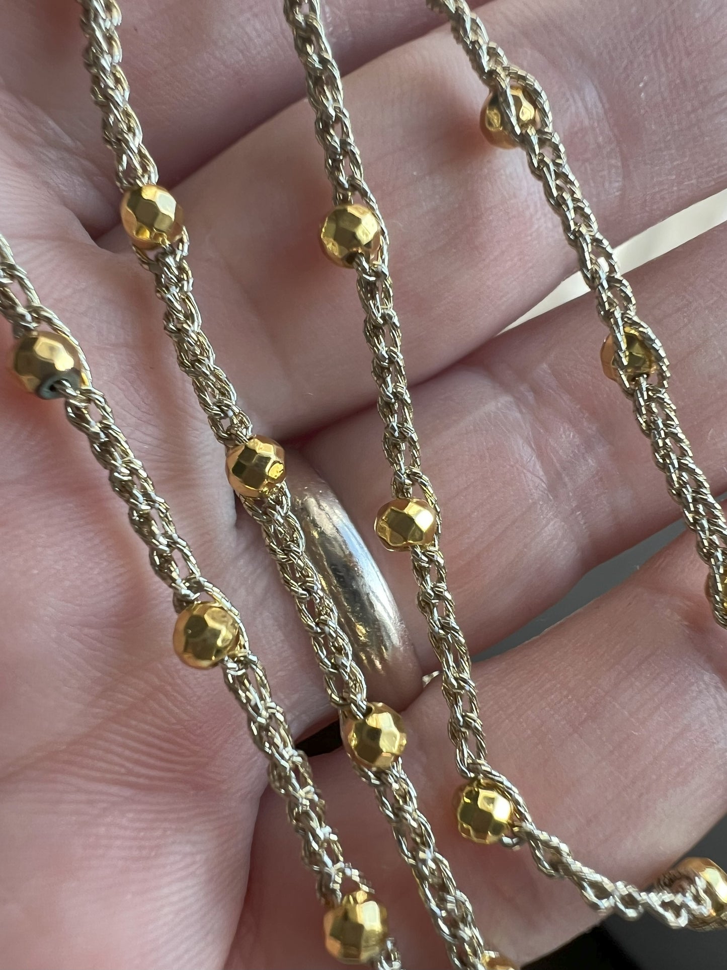 Collana minimalista in filato dorato con piccole pietre di ematite color oro, design elegante e senza chiusura, realizzata con materiali anallergici, ideale per uno stile pratico e raffinato