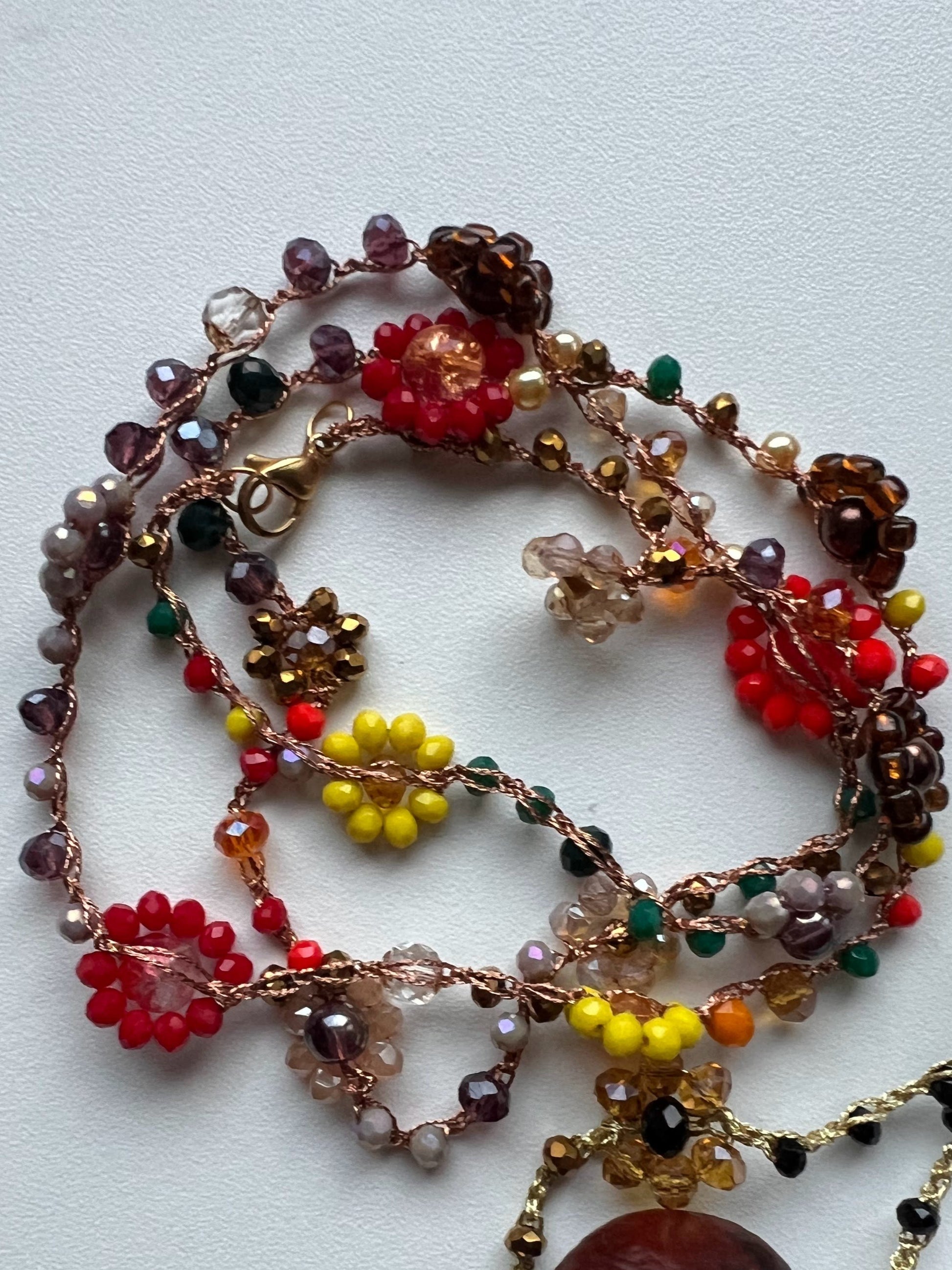 Girocollo "Essenza d'Autunno" realizzato a mano con fiori naturali e perle in tonalità calde, ispirato ai colori dell'autunno. Versatile e regolabile, può essere indossato come collana o bracciale avvolgente, perfetto per ogni occasione. Un accessorio unico che riflette la bellezza naturale e l'eleganza, ideale per chi desidera esprimere la propria personalità attraverso gioielli artigianali.