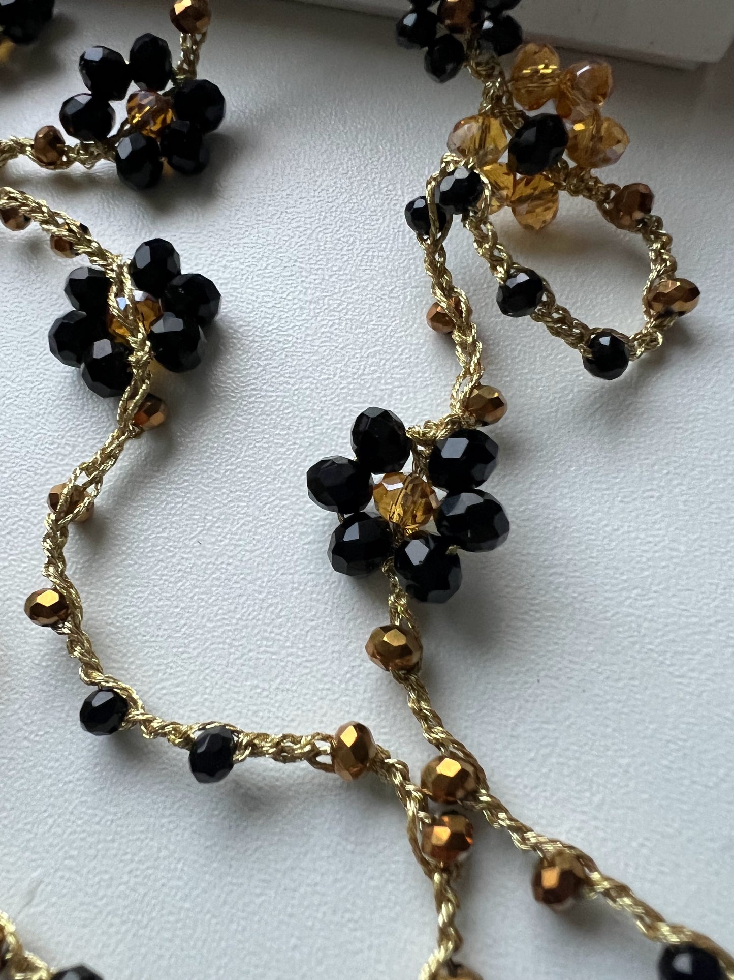 Collana lunga boho chic in oro nero con cristalli e fiori, versatile da indossare come collana o bracciale wrap, perfetta per aggiungere un tocco di eleganza e personalità al tuo look.