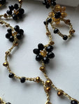 Collana lunga boho chic in oro nero con cristalli e fiori, versatile da indossare come collana o bracciale wrap, perfetta per aggiungere un tocco di eleganza e personalità al tuo look.