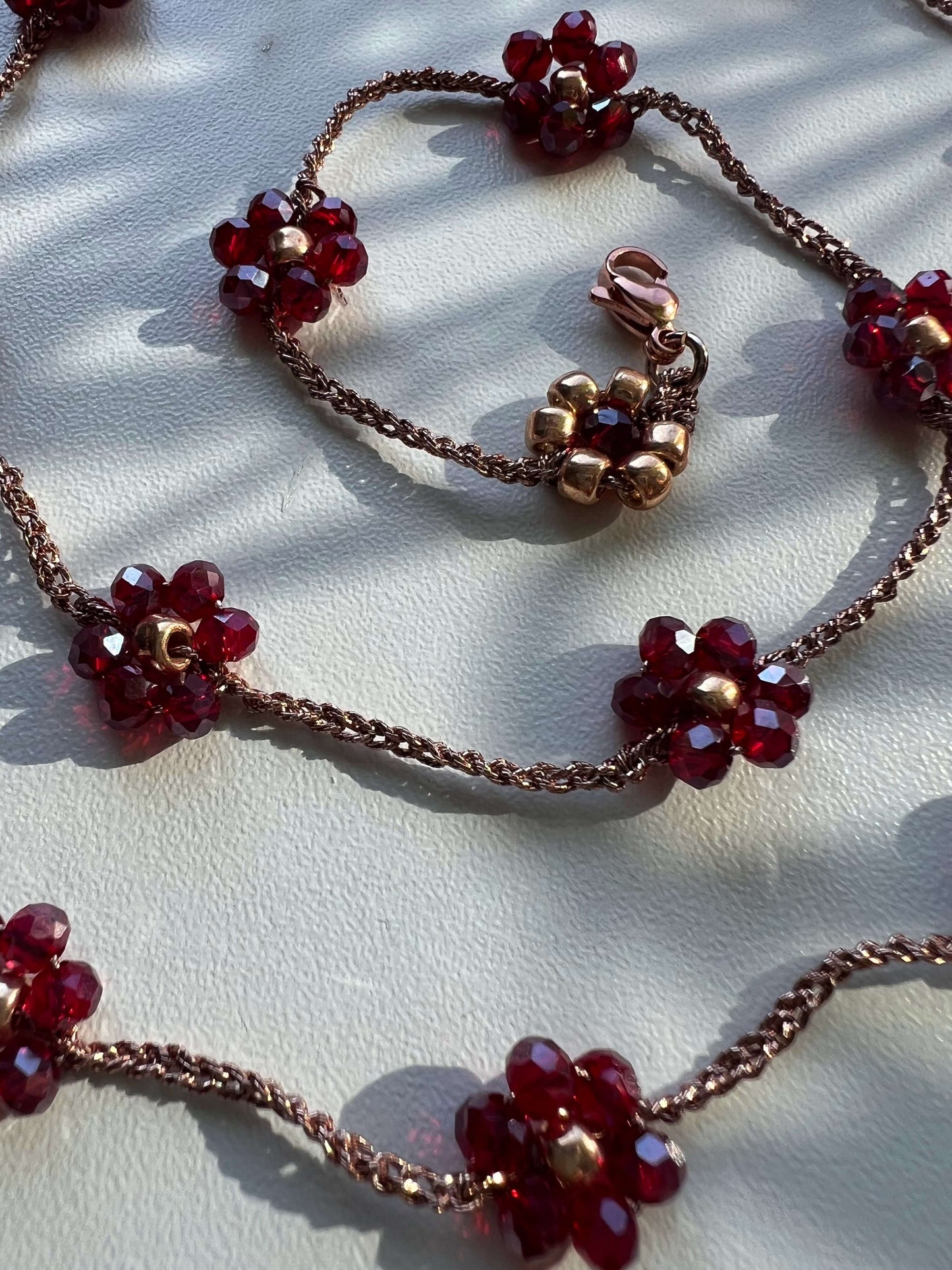 Dettaglio collana “Melograno d’Oro” in oro rosa e fiori melograno, artigianale e raffinata, per uno stile elegante ogni giorno.