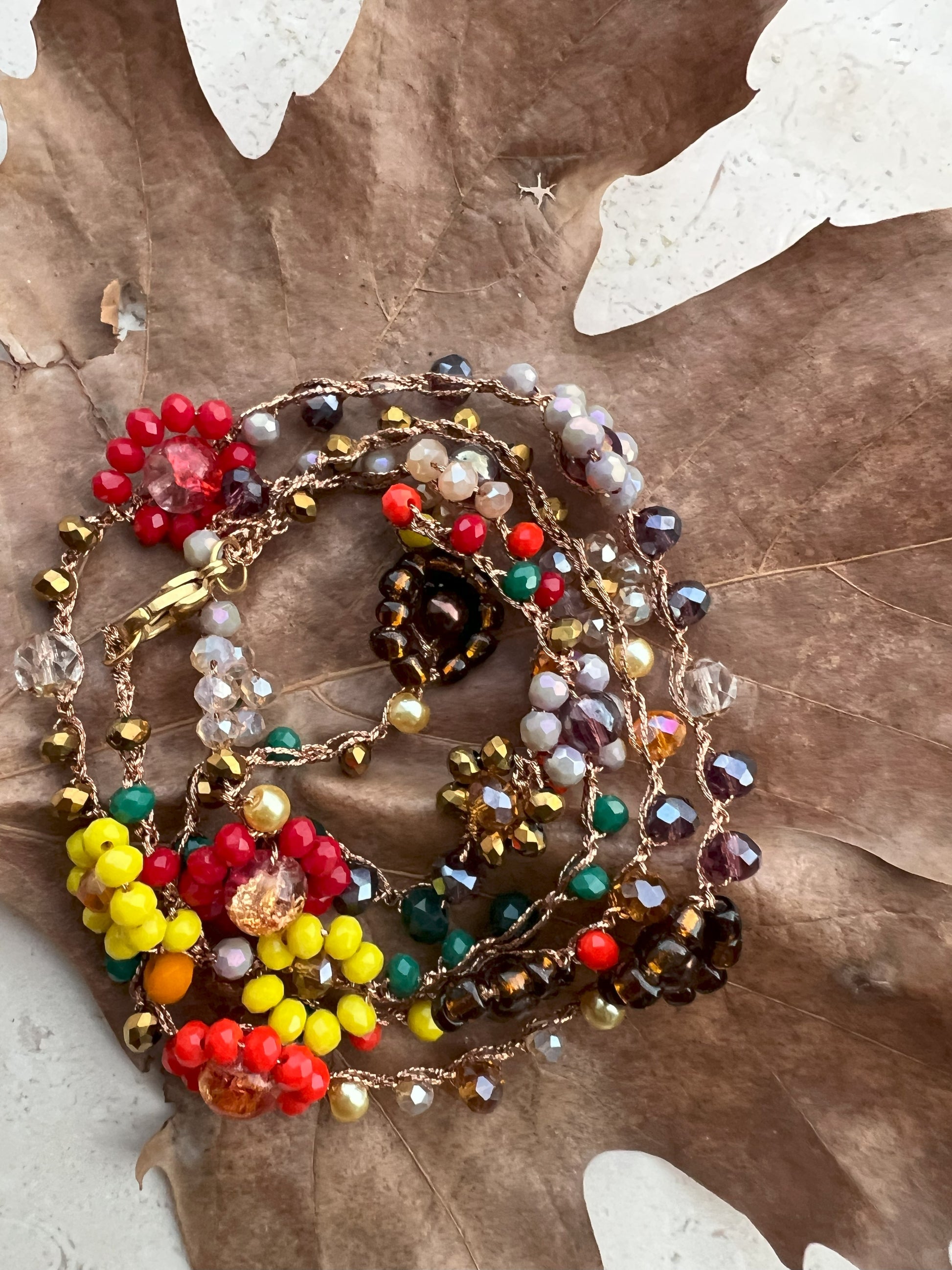 Girocollo "Essenza d'Autunno" realizzato a mano con fiori naturali e perle in tonalità calde, ispirato ai colori dell'autunno. Versatile e regolabile, può essere indossato come collana o bracciale avvolgente, perfetto per ogni occasione. Un accessorio unico che riflette la bellezza naturale e l'eleganza, ideale per chi desidera esprimere la propria personalità attraverso gioielli artigianali.