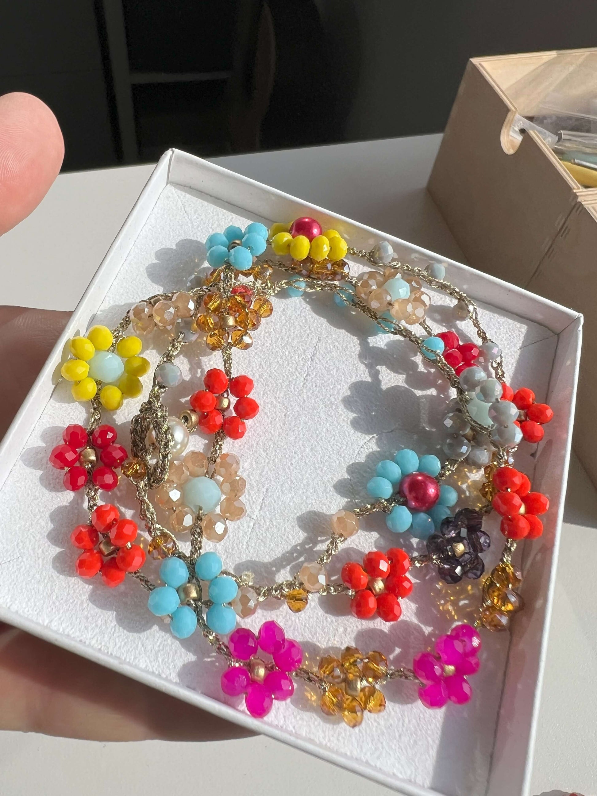 Gioiello trasformabile Primavera Improvvisa: collana uncinetto 61cm con fiori. Design italiano versatile, indossabile come collana o bracciale wrap