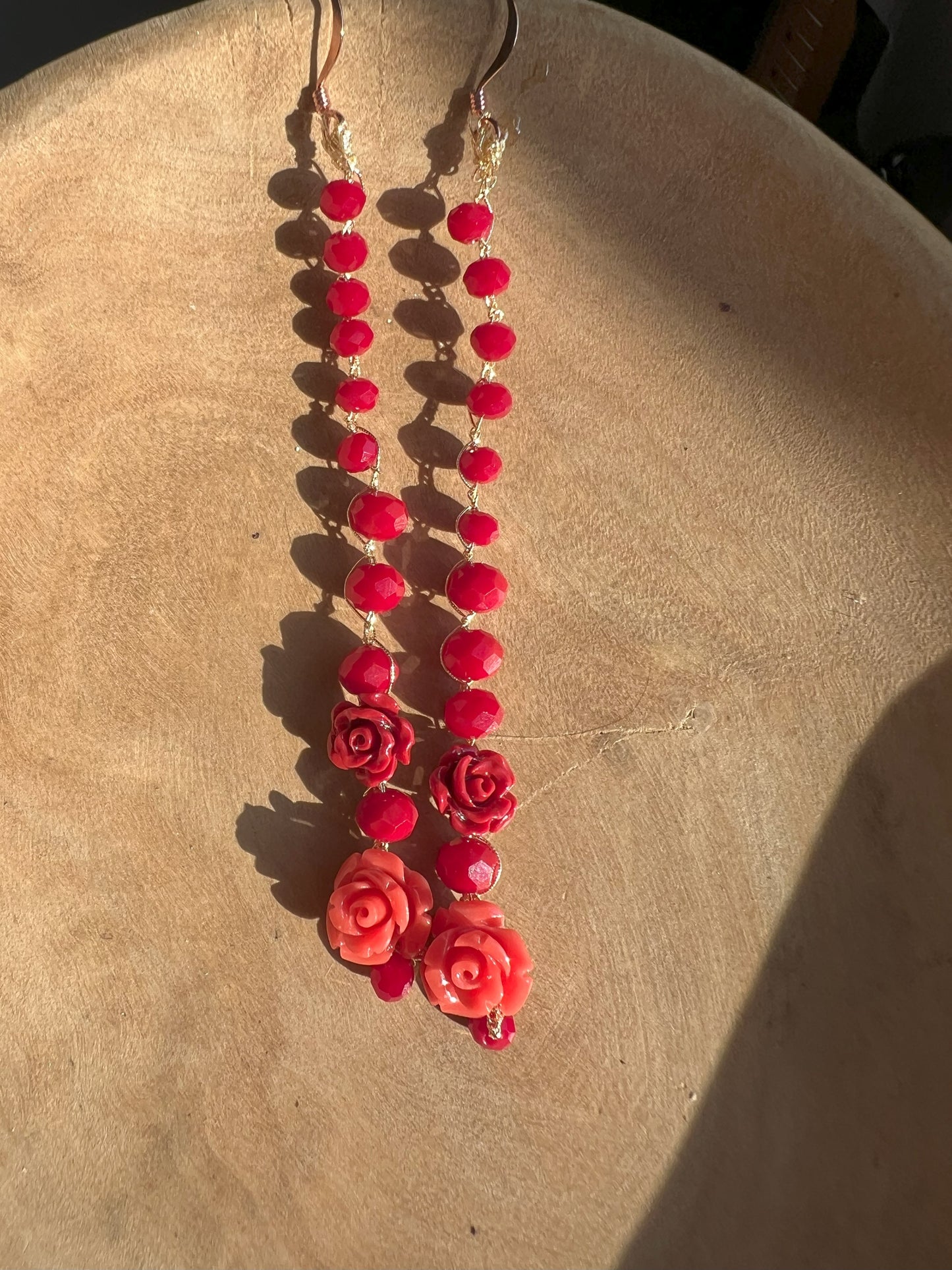 Orecchini "Soffio di Rosa" con cristalli rossi e le rose di corallo naturale, un elegante accessorio artigianale per un tocco raffinato.