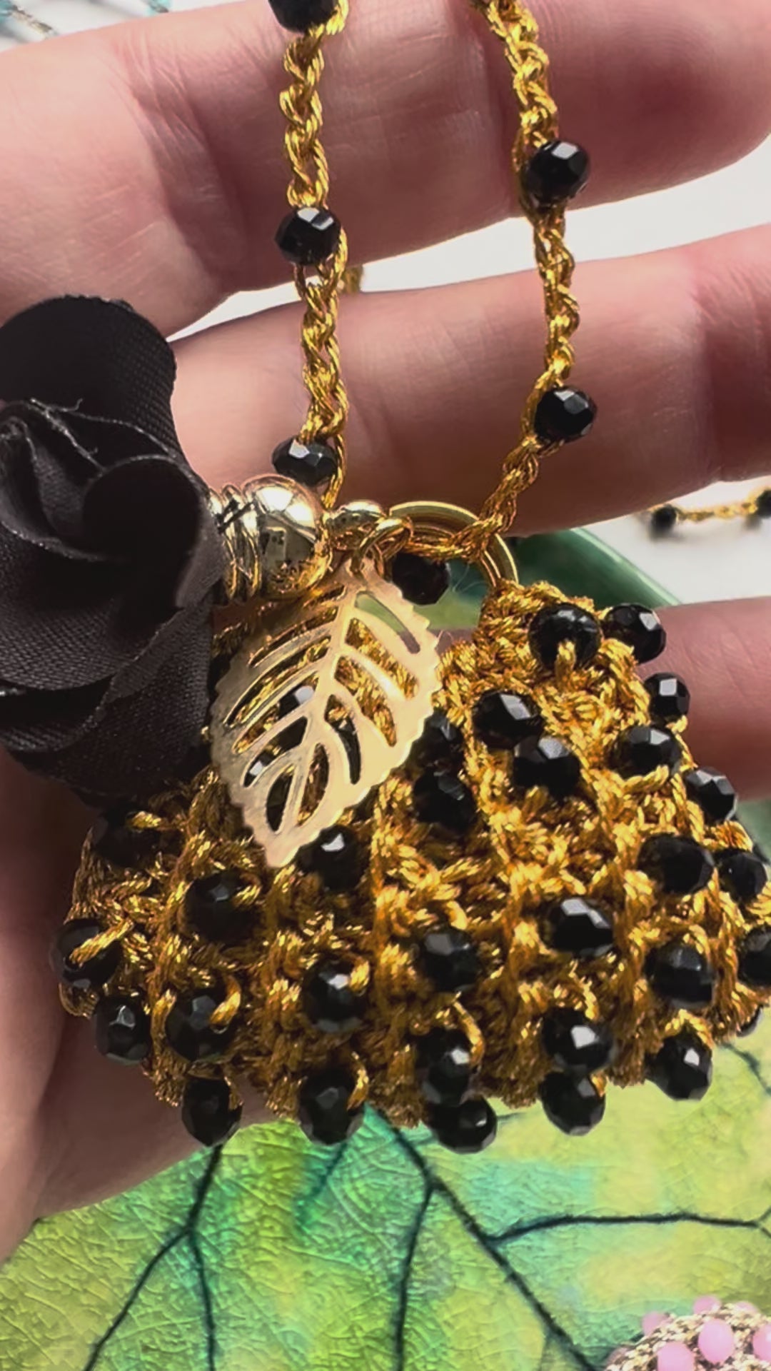 Close-up of handmade mini bag pendant necklace in black crystals with floral charms – perfect gift for women