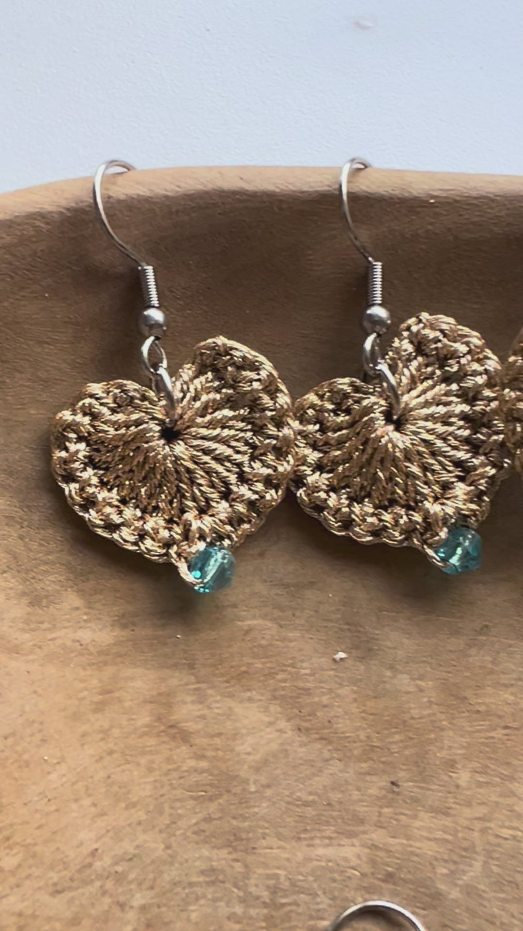 Delicate handmade heart earrings with a touch of gold and a blue crystal at the center