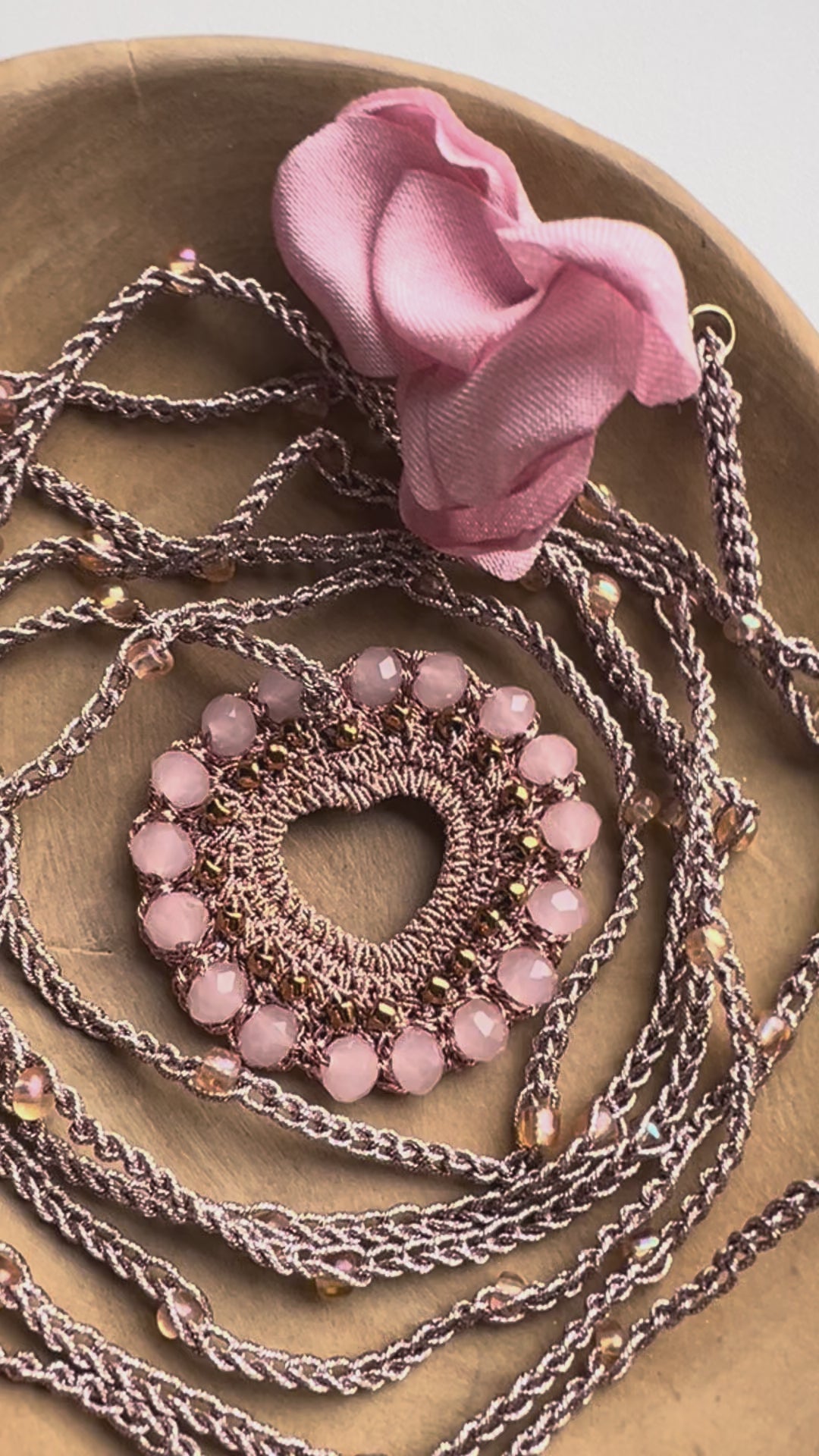 Collana lunga cuore rosa cipria con dettagli rame e petali, gioiello boho elegante perfetto per look sofisticati e romantici.