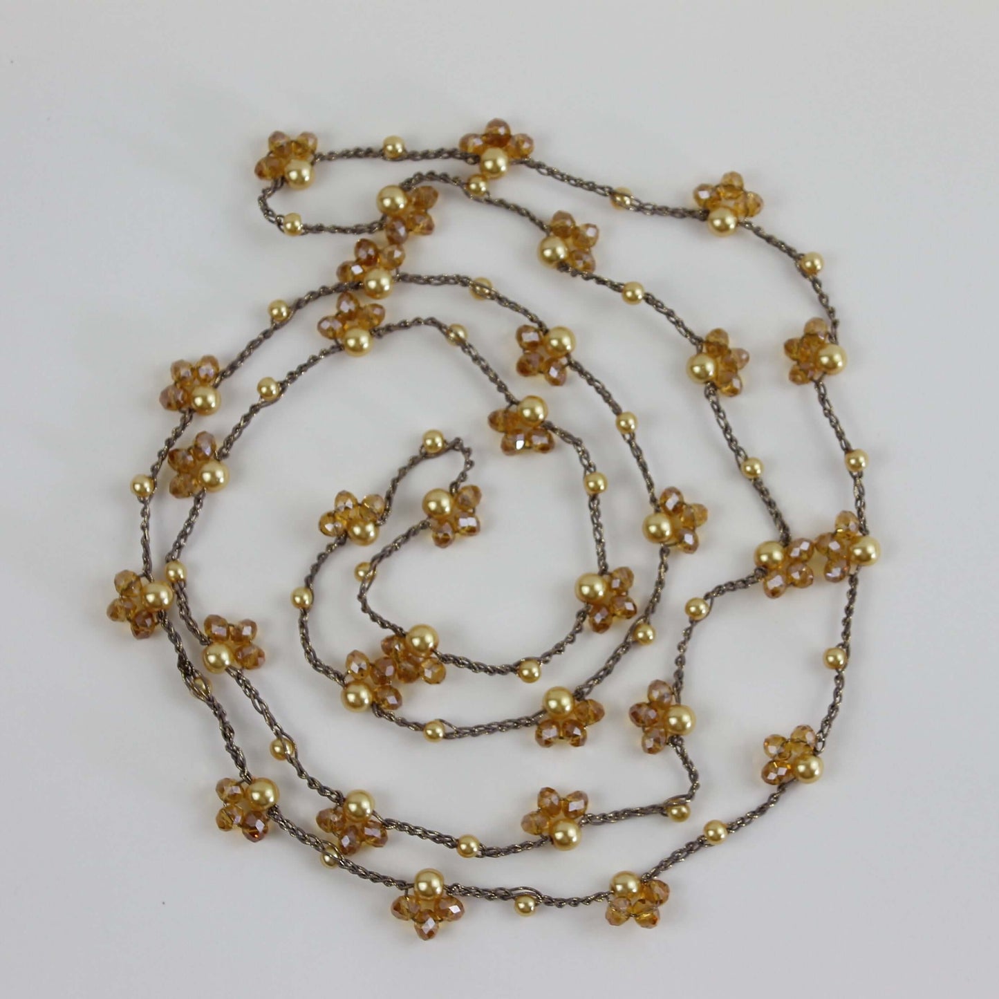 Collana artigianale lunga Fafiki, realizzata a mano con filo color oro, perline e cristalli. Versatile e comoda, può essere indossata in un giro o avvolta due volte per un look sofisticato. La chiusura assente la rende facile da indossare, mentre il design anallergico la rende ideale per chi cerca comfort. Usa la collana anche come bracciale multigiro per esprimere la tua creatività