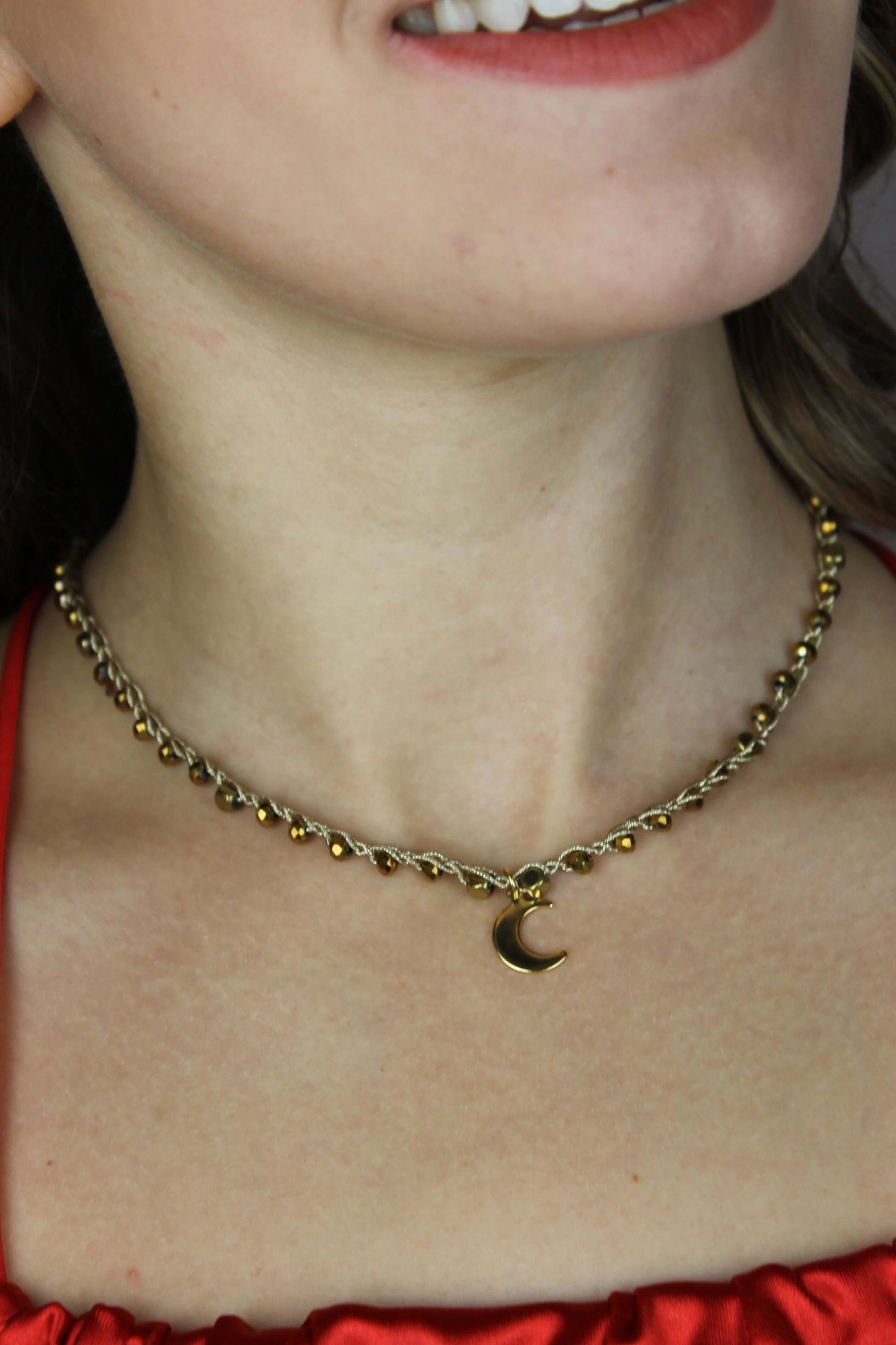 Girocollo artigianale Fafiki in color oro, realizzato con cristalli dorati e pietre di ematite color oro. Caratterizzato da una delicata luna in acciaio inossidabile, questo gioiello lungo 42 cm è dotato di chiusura a moschettone in acciaio galvanizzato. Perfetto per chi cerca un accessorio elegante e versatile, questo girocollo aggiunge un tocco di stile unico a ogni outfit, rendendolo un regalo ideale per le occasioni speciali.