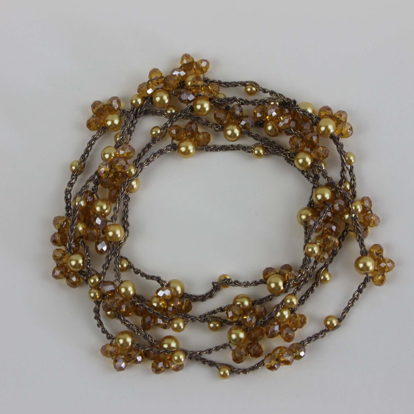 Collana artigianale lunga Fafiki, realizzata a mano con filo color oro, perline e cristalli. Versatile e comoda, può essere indossata in un giro o avvolta due volte per un look sofisticato. La chiusura assente la rende facile da indossare, mentre il design anallergico la rende ideale per chi cerca comfort. Usa la collana anche come bracciale multigiro per esprimere la tua creatività