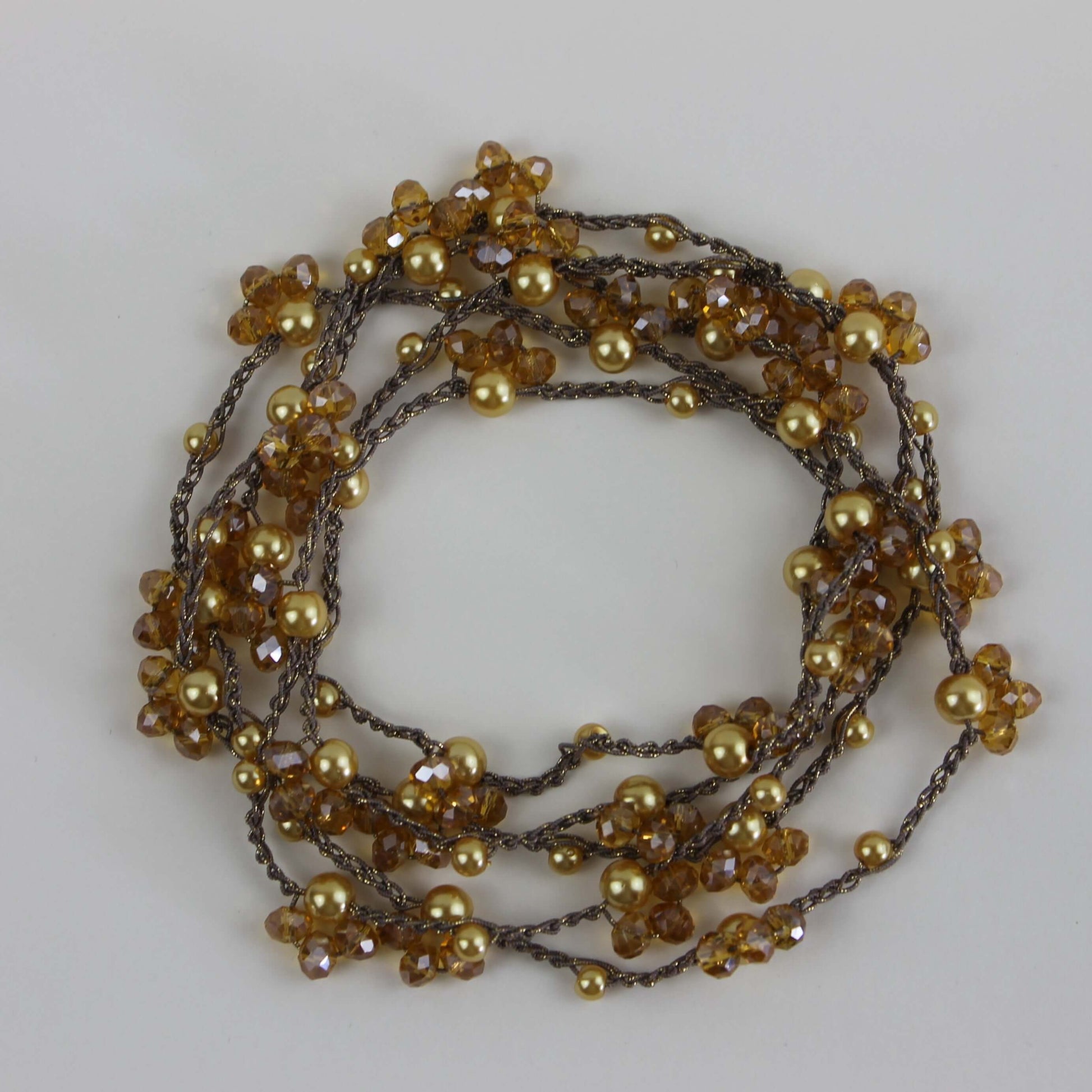 Collana artigianale lunga Fafiki, realizzata a mano con filo color oro, perline e cristalli. Versatile e comoda, può essere indossata in un giro o avvolta due volte per un look sofisticato. La chiusura assente la rende facile da indossare, mentre il design anallergico la rende ideale per chi cerca comfort. Usa la collana anche come bracciale multigiro per esprimere la tua creatività