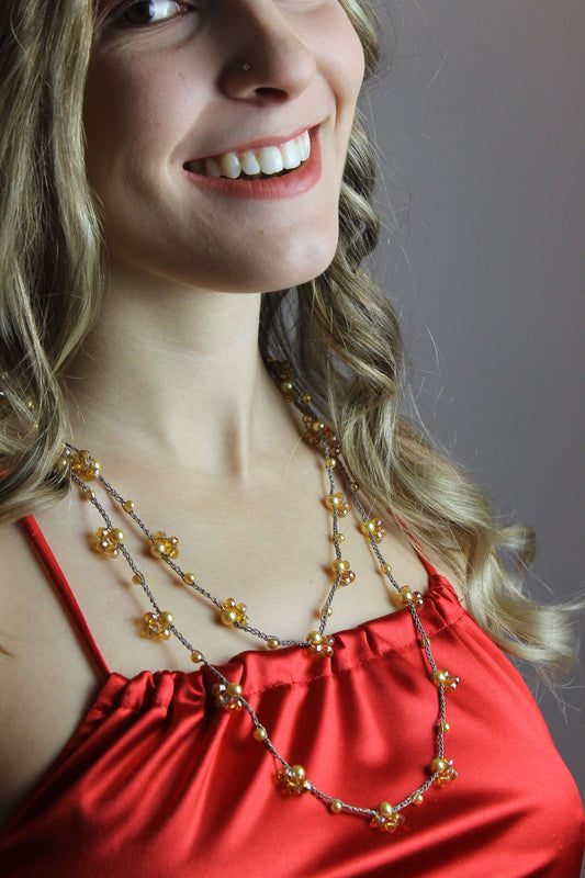 Collana artigianale lunga Fafiki, realizzata interamente a mano all’uncinetto con pregiato filo color oro, perline e cristalli. Questo gioiello versatile è pensato per te, che cerchi un accessorio elegante e funzionale. Con una lunghezza di 60 cm, puoi indossarla in un solo giro per un look semplice o avvolgerla due volte per un effetto più sofisticato. La sua struttura senza chiusura la rende comoda e veloce da indossare, perfetta per la tua vita frenetica. Inoltre, la collana è completamente anallergica.