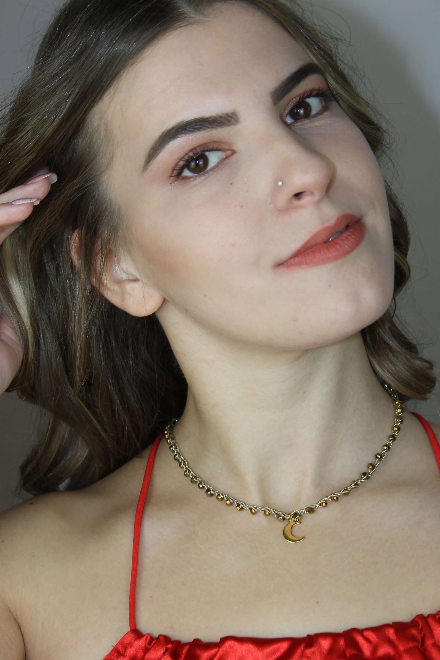 Girocollo artigianale Fafiki in color oro, realizzato con cristalli dorati e pietre di ematite color oro. Caratterizzato da una delicata luna in acciaio inossidabile, questo gioiello lungo 42 cm è dotato di chiusura a moschettone in acciaio galvanizzato. Perfetto per chi cerca un accessorio elegante e versatile, questo girocollo aggiunge un tocco di stile unico a ogni outfit, rendendolo un regalo ideale per le occasioni speciali.