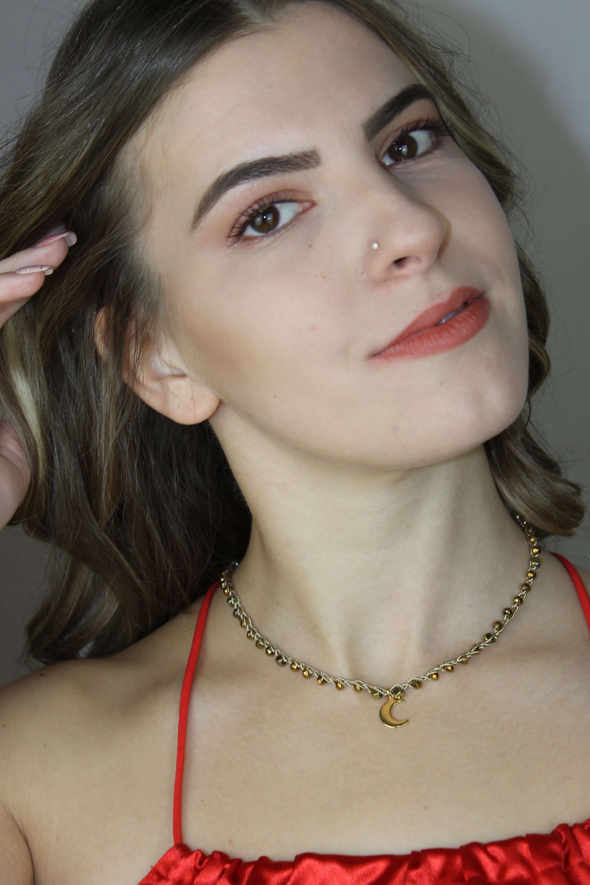 Girocollo artigianale Fafiki in color oro, realizzato con cristalli dorati e pietre di ematite color oro. Caratterizzato da una delicata luna in acciaio inossidabile, questo gioiello lungo 42 cm è dotato di chiusura a moschettone in acciaio galvanizzato. Perfetto per chi cerca un accessorio elegante e versatile, questo girocollo aggiunge un tocco di stile unico a ogni outfit, rendendolo un regalo ideale per le occasioni speciali.