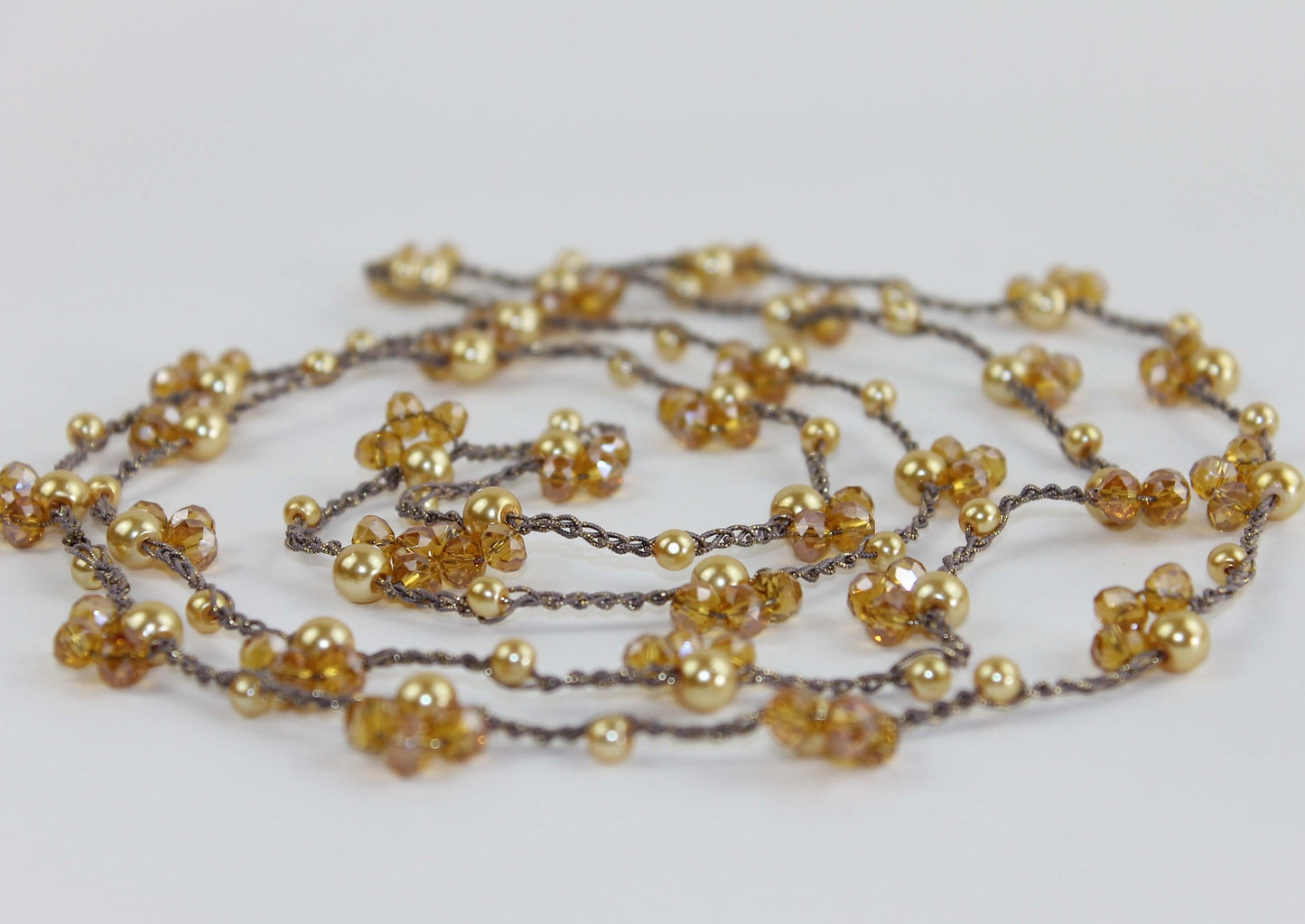 Collana artigianale lunga Fafiki, realizzata a mano con filo color oro, perline e cristalli. Versatile e comoda, può essere indossata in un giro o avvolta due volte per un look sofisticato. La chiusura assente la rende facile da indossare, mentre il design anallergico la rende ideale per chi cerca comfort. Usa la collana anche come bracciale multigiro per esprimere la tua creatività